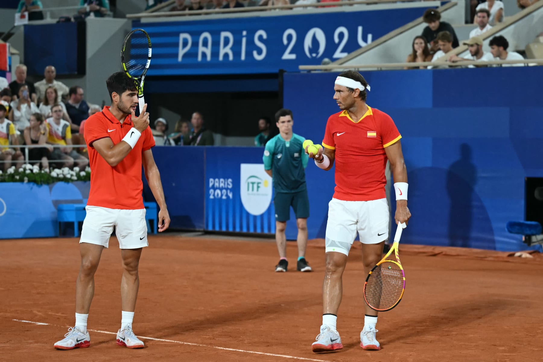 Spain's Rafael Nadal (R) and Spain's Carlos Alcaraz (R) speak while playing US' Austin Krajicek and US' Rajeev Ram during their men's doubles quarter-final tennis match on Court Philippe-Chatrier at the Roland-Garros Stadium during the Paris 2024 Olympic Games, in Paris on July 31, 2024. (Photo by CARL DE SOUZA / AFP) (Photo by CARL DE SOUZA/AFP via Getty Images)