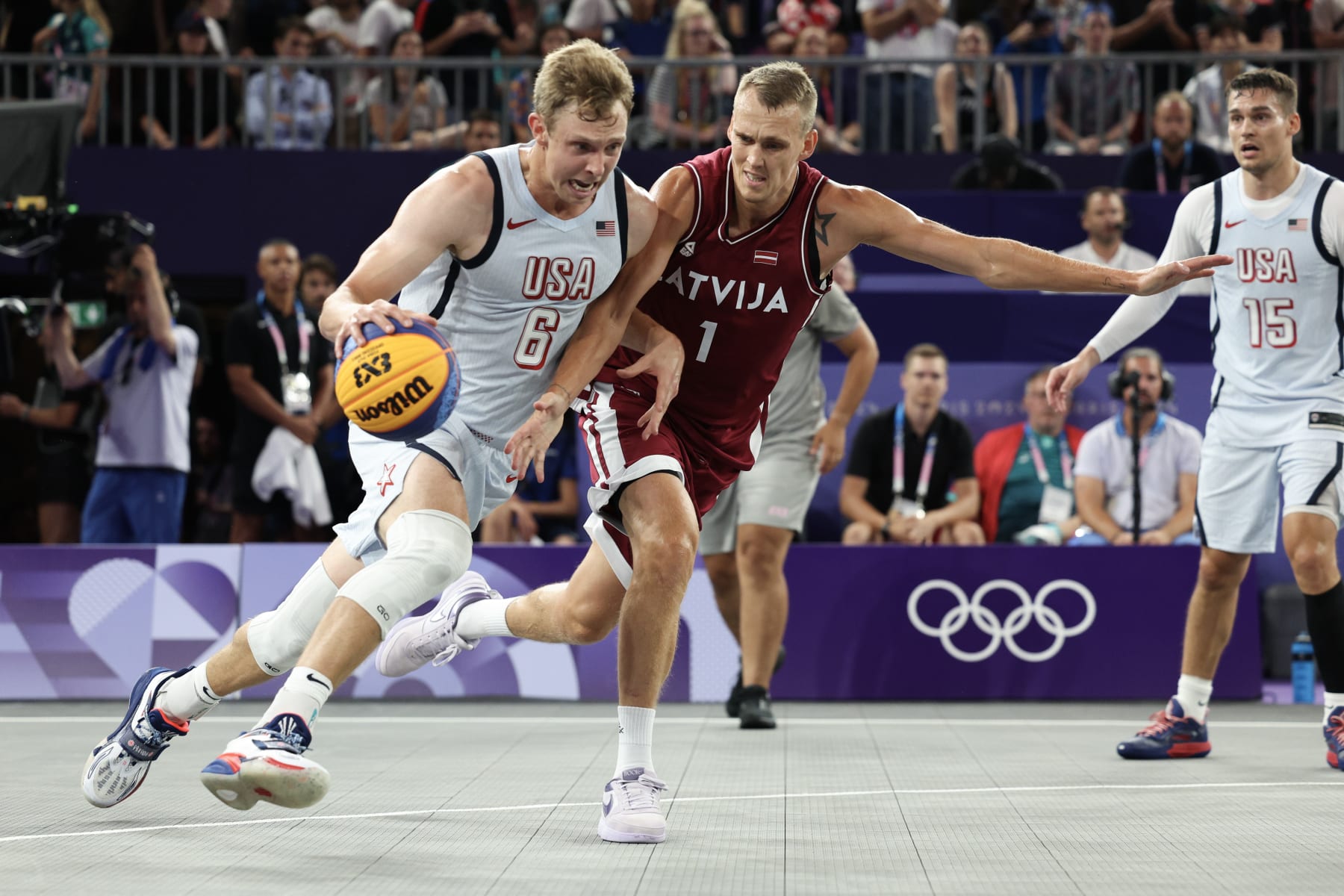 PARIS, FRANCE - AUGUST 01: Canyon Barry #6 of Team United States drives past Nauris Miezis #1 of Team Latvia during a Men's 3x3 basketball pool round game between United States and Latvia on day six of the Olympic Games Paris 2024 at Esplanade Des Invalides on August 01, 2024 in Paris, France. (Photo by Elsa/Getty Images)