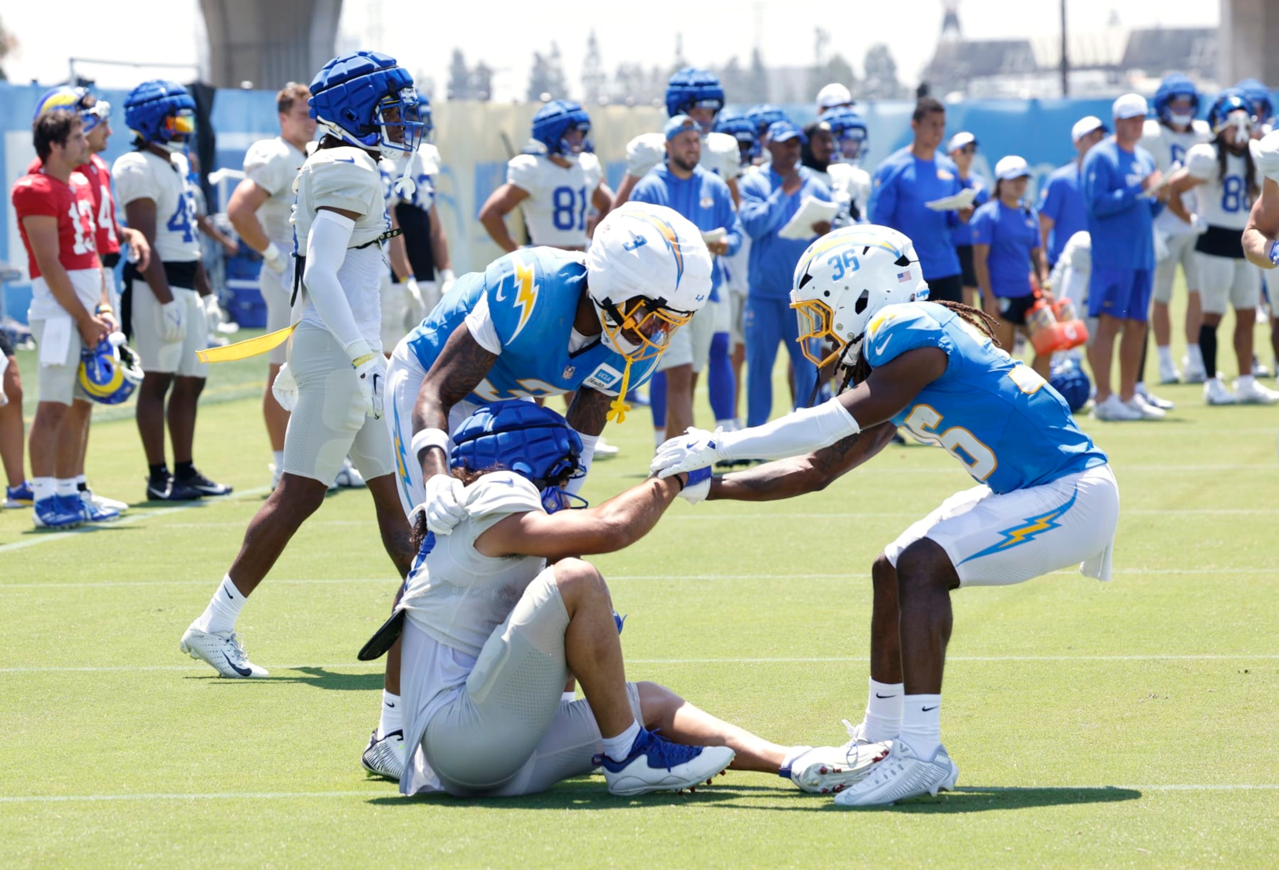 EL SEGUNDO, CALIFORNIA - AUGUST 4: Wide receiver Puka Nacua #17 of the Los Angeles Rams is helped up by safety Derwin James Jr. #3 and safety Alohi Gilman #32 of the Los Angeles Chargers after Nacua was tackled by Gilman #32  during joint practice at The Bolt on August 4, 2024 in El Segundo, California. (Photo by Kevork Djansezian/Getty Images)