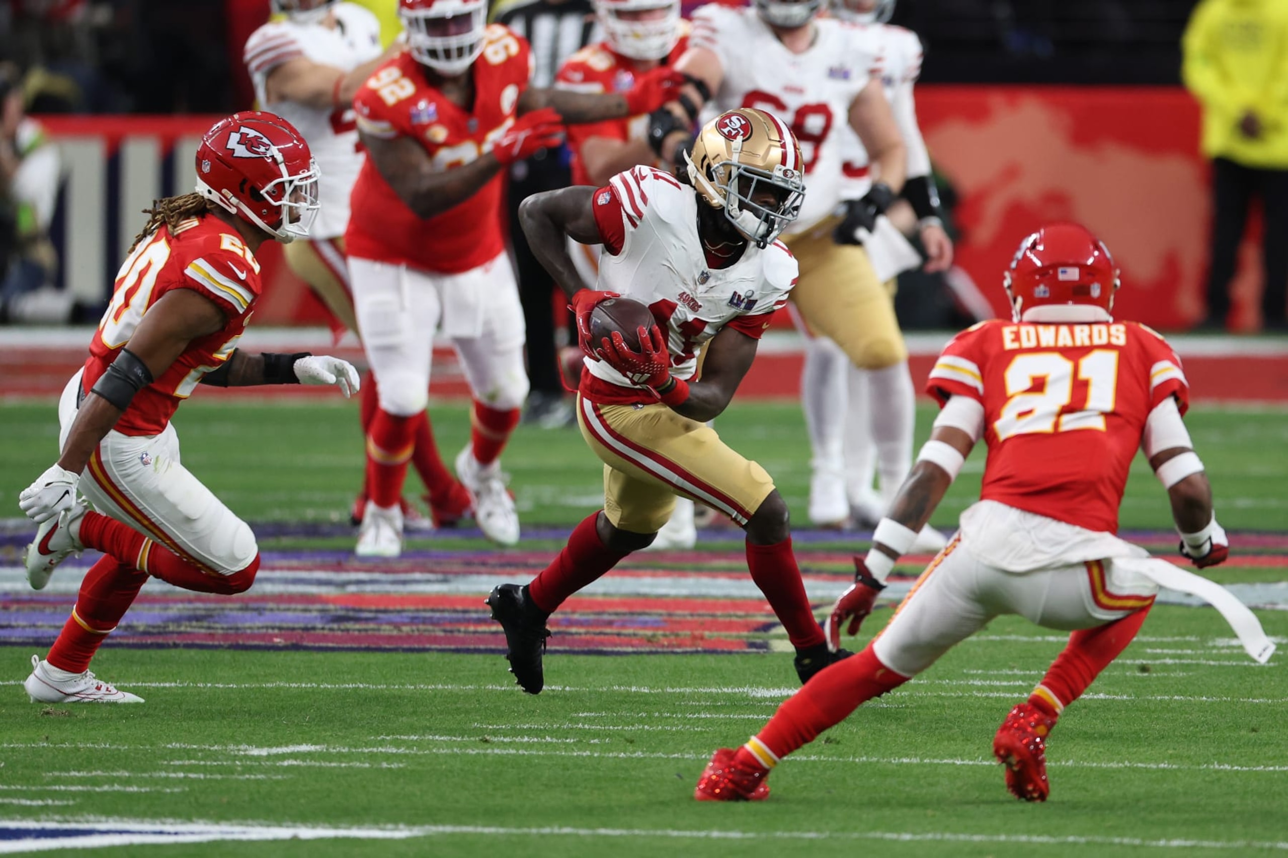 LAS VEGAS, NEVADA - FEBRUARY 11: Brandon Aiyuk #11 of the San Francisco 49ers runs the ball after a catch for a first down while defended by Justin Reid #20 and Mike Edwards #21 of the Kansas City Chiefs during the first quarter during Super Bowl LVIII at Allegiant Stadium on February 11, 2024 in Las Vegas, Nevada. (Photo by Harry How/Getty Images)