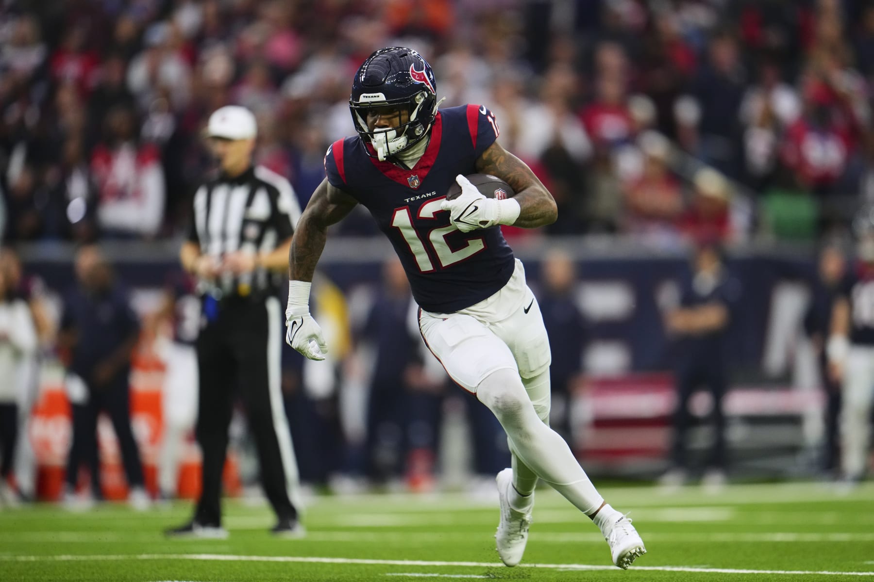 HOUSTON, TX - JANUARY 13: Nico Collins #12 of the Houston Texans runs with the ball against the Cleveland Browns during the first half of the AFC Wild Card playoff game at NRG Stadium on January 13, 2024 in Houston, Texas. (Photo by Cooper Neill/Getty Images)