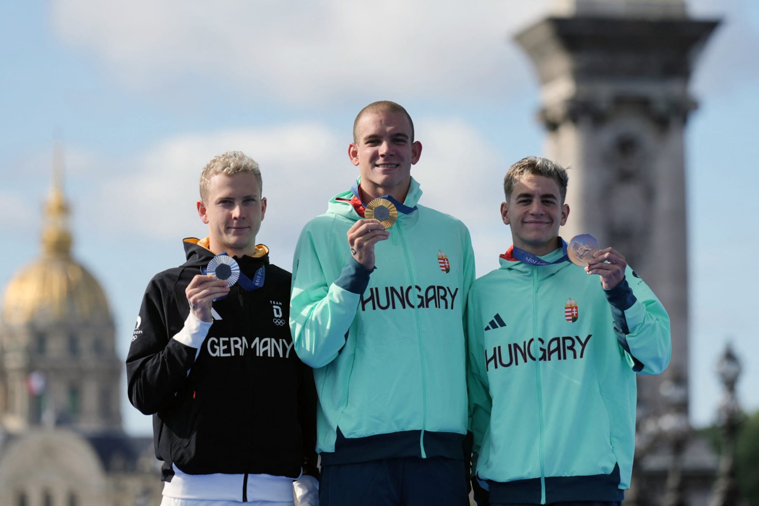 (LtoR) Silver medallist Germany's Oliver Klemet, gold medallist Hungary's Kristof Rasovszky and bronze medallist Hungary's David Betlehem pose on the podium during the award ceremony for the men's 10km marathon swimming final at the Paris 2024 Olympic Games at Pont Alexandre III in Paris on August 9, 2024. (Photo by Dimitar DILKOFF / AFP) (Photo by DIMITAR DILKOFF/AFP via Getty Images)