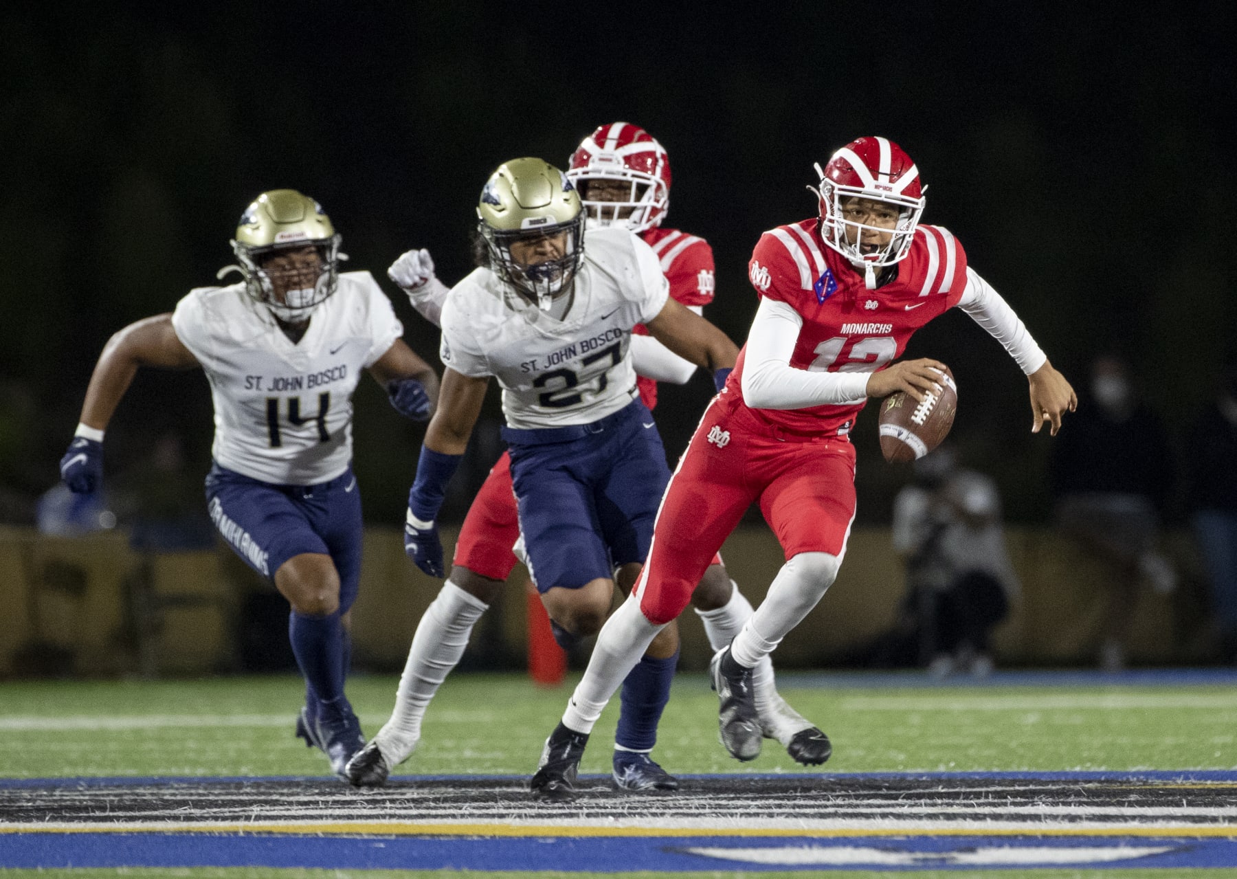 SANTA ANA, CA - APRIL 17, 2021: Mater Dei quarterback Elijah Brown scampers for extra yardage while St John Bosco defenders Benny Lockhart (14) and Kyngstonn Villiamu-Asa (27) give chase at Santa Ana Stadium on April 17, 2021 in Santa Ana California.(Gina Ferazzi / Los Angeles Times via Getty Images)