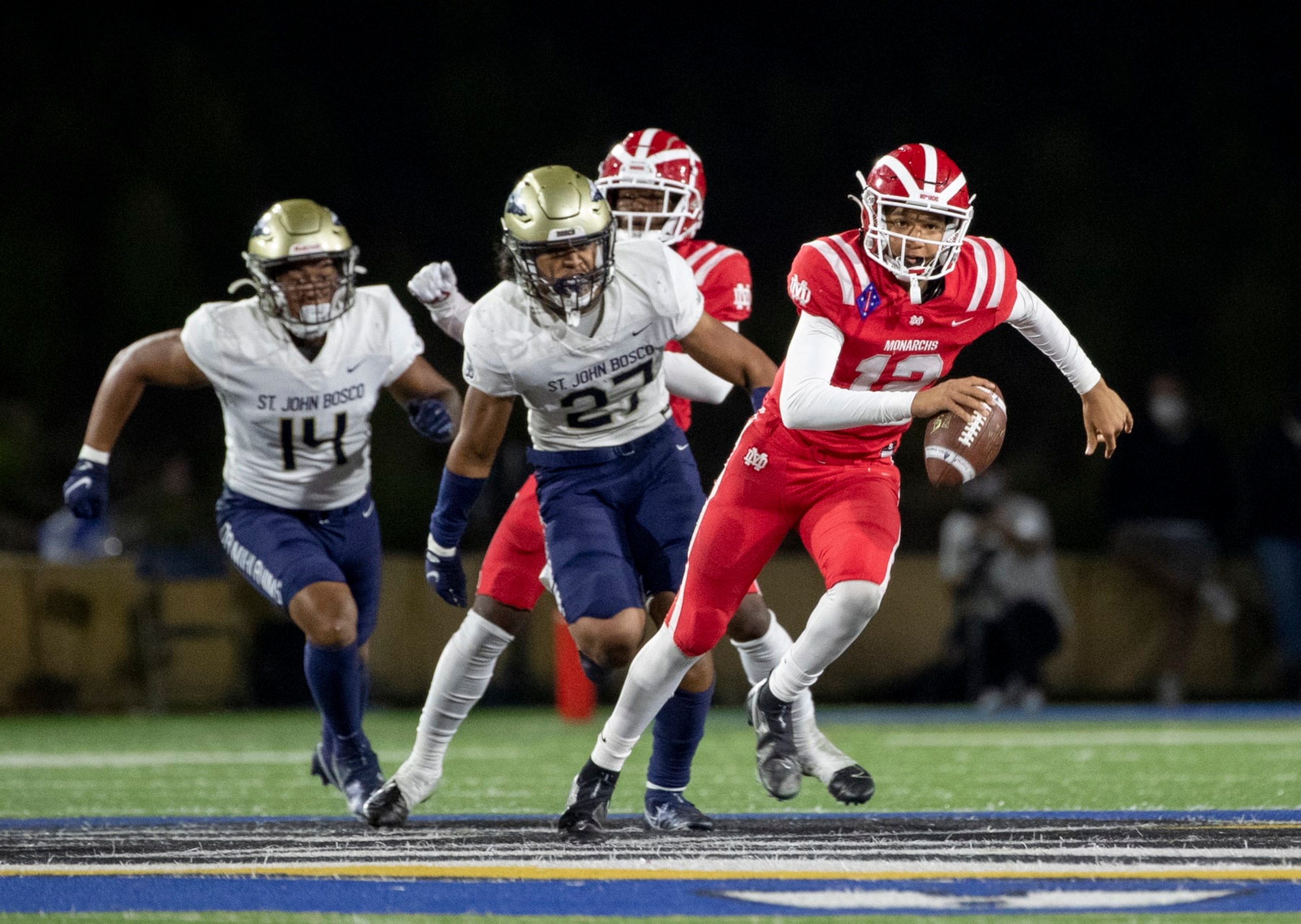 SANTA ANA, CA - APRIL 17, 2021: Mater Dei quarterback Elijah Brown scampers for extra yardage while St John Bosco defenders Benny Lockhart (14) and Kyngstonn Villiamu-Asa (27) give chase at Santa Ana Stadium on April 17, 2021 in Santa Ana California.(Gina Ferazzi / Los Angeles Times via Getty Images)