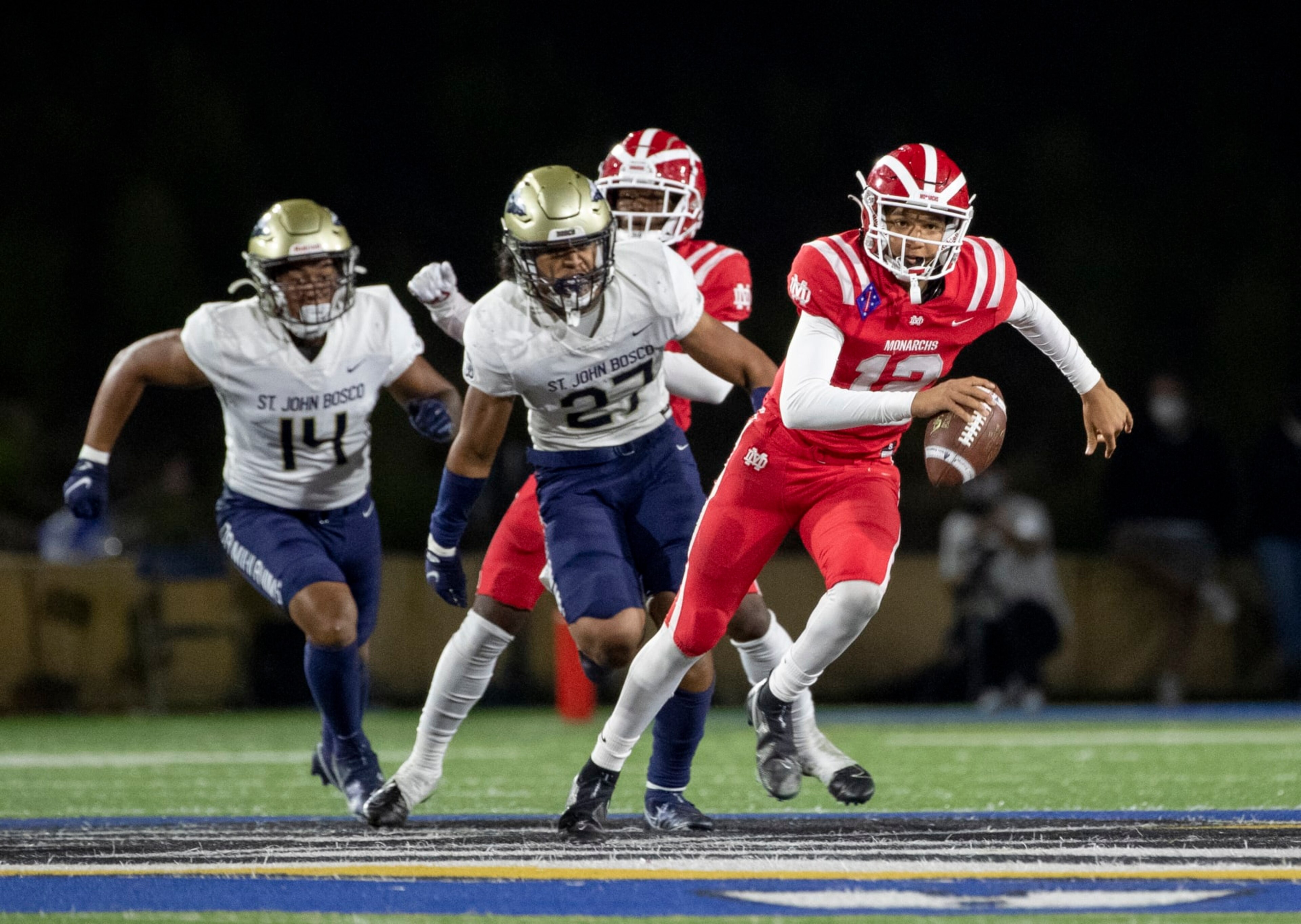 SANTA ANA, CA - APRIL 17, 2021: Mater Dei quarterback Elijah Brown scampers for extra yardage while St John Bosco defenders Benny Lockhart (14) and Kyngstonn Villiamu-Asa (27) give chase at Santa Ana Stadium on April 17, 2021 in Santa Ana California.(Gina Ferazzi / Los Angeles Times via Getty Images)