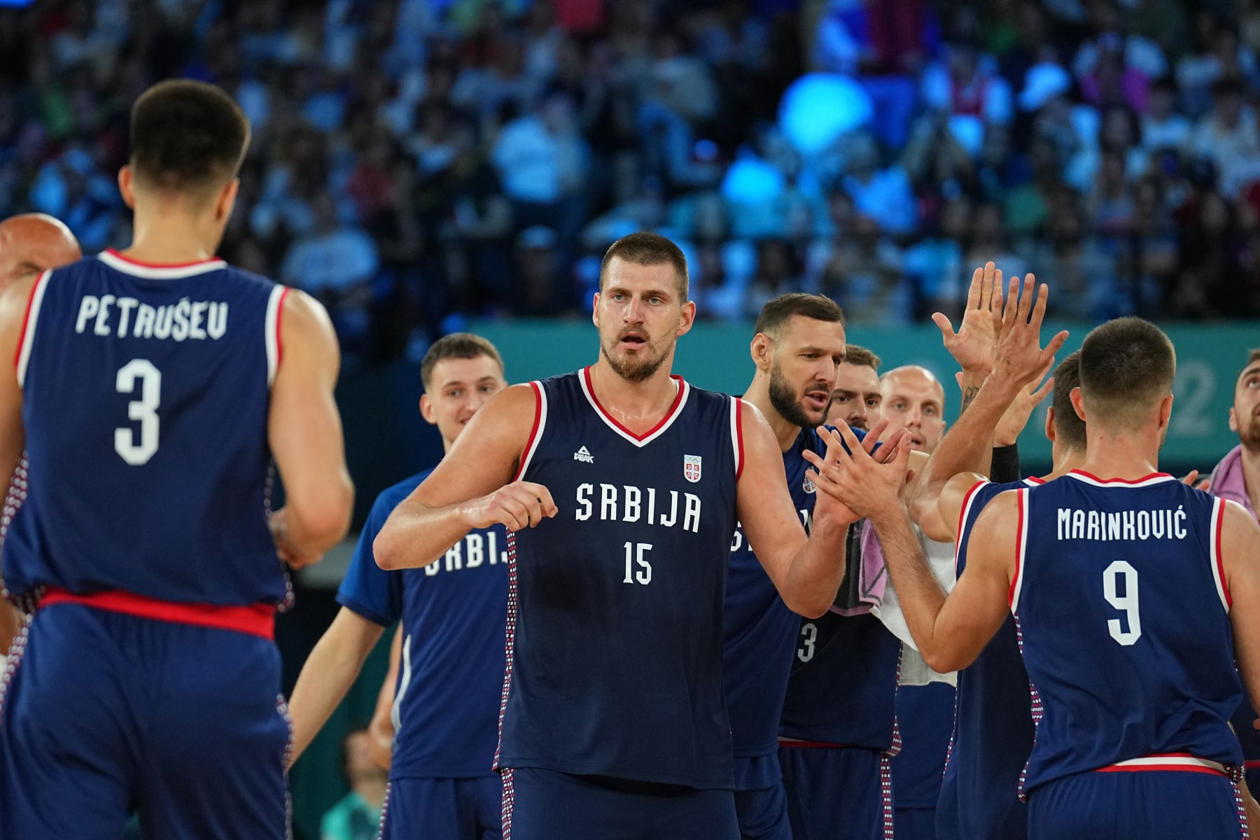 PARIS, FRANCE - AUGUST 10:  Nikola Jokic #15 of the Serbian Men's National Team and Vanja Marinkovic #9 of the Serbian Men's National Team high five during the game during the Mens Bronze Medal game at the  AccorHotels Arena on August 10, 2024 in Lille, France. NOTE TO USER: User expressly acknowledges and agrees that, by downloading and/or using this photograph, user is consenting to the terms and conditions of the Getty Images License Agreement. Mandatory Copyright Notice: Copyright 2024 NBAE (Photo by Garrett W. Ellwood/NBAE via Getty Images)