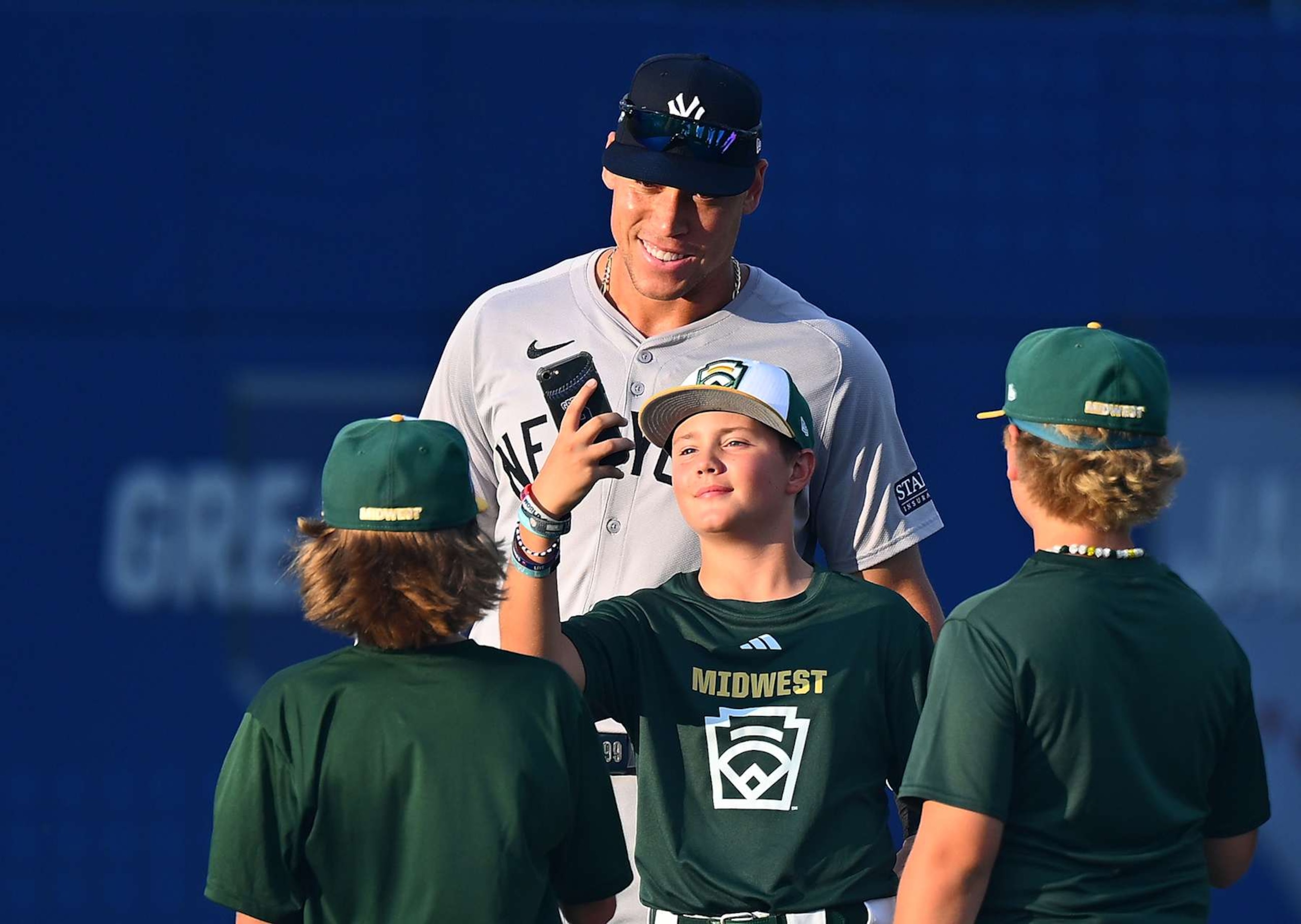 SOUTH WILLIAMSPORT, PENNSYLVANIA - AUGUST 18:  Aaron Judge #99 of the New York Yankees takes photos with Little League players prior to the game against the Detroit Tigers  at Bowman Field on August 18, 2024 in South Williamsport, Pennsylvania. (Photo by Joe Sargent/Getty Images)