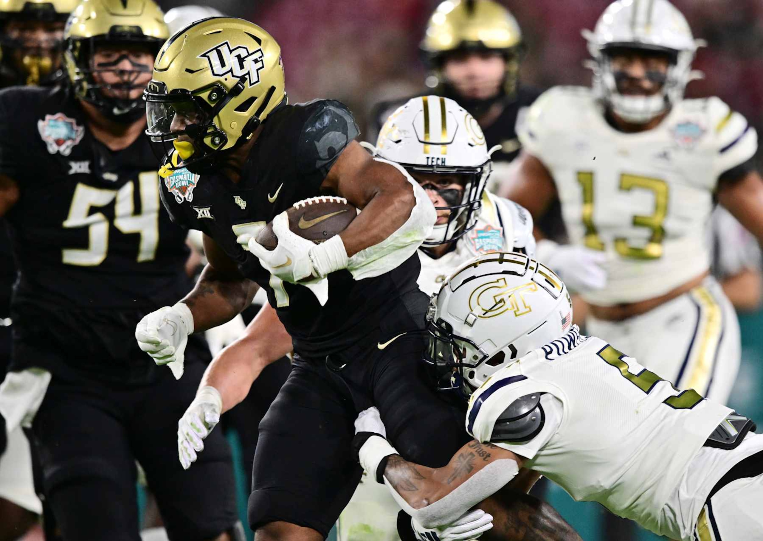 TAMPA, FLORIDA - DECEMBER 22: RJ Harvey #7 of the UCF Knights rushes the ball against Clayton Powell-Lee #5 of the Georgia Tech Yellow Jackets in the first quarter during the 2023 Union Home Mortgage Gasparilla Bowl at Raymond James Stadium on December 22, 2023 in Tampa, Florida. (Photo by Julio Aguilar/Getty Images) TAMPA, FLORIDA - DECEMBER 22: RJ Harvey #7 of the UCF Knights rushes the ball against Clayton Powell-Lee #5 of the Georgia Tech Yellow Jackets in the first quarter during the 2023 Union Home Mortgage Gasparilla Bowl at Raymond James Stadium on December 22, 2023 in Tampa, Florida. (Photo by Julio Aguilar/Getty Images)