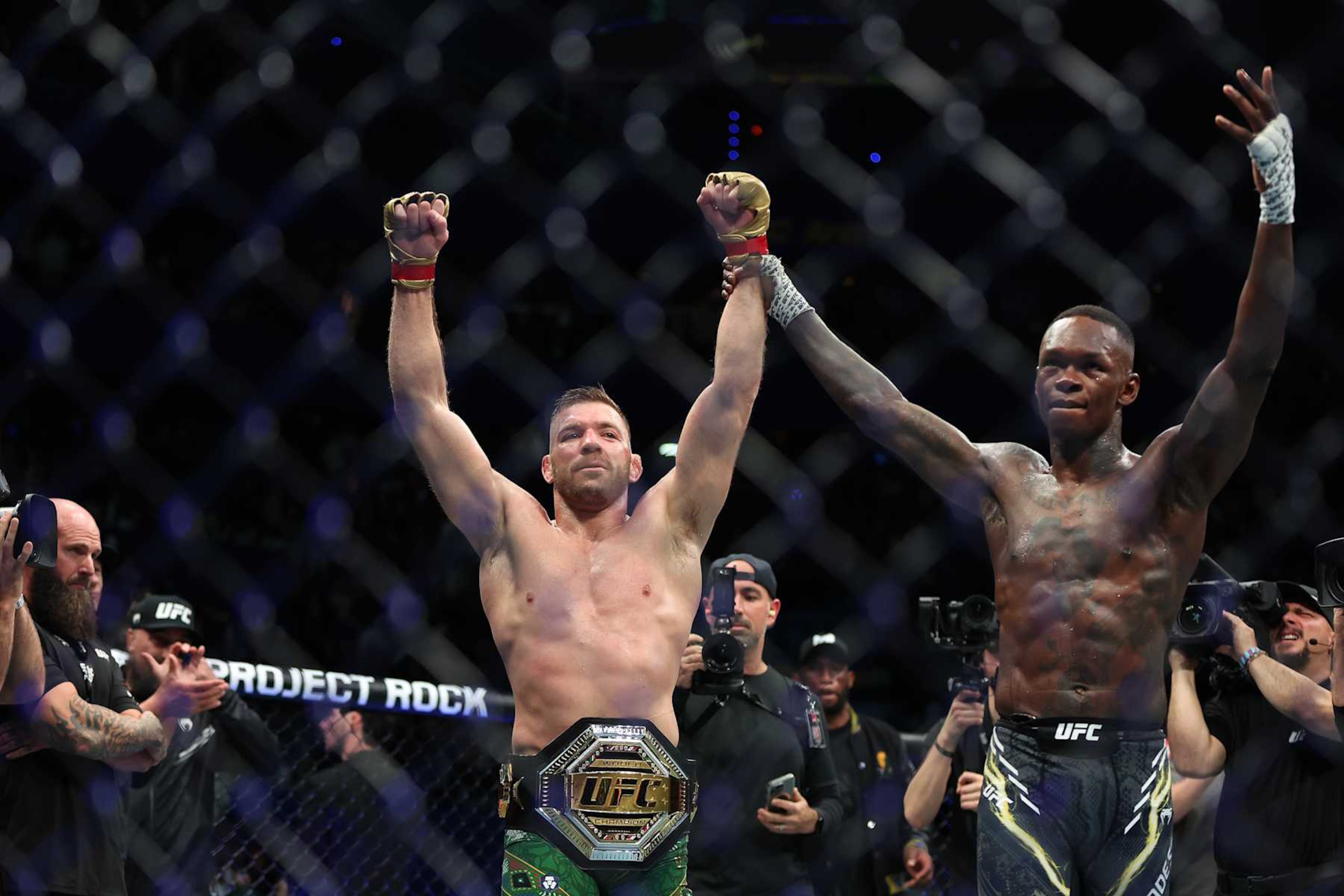 Dricus Du Plessis of South Africa has his arm raised by Israel Adesanya of Nigeria.