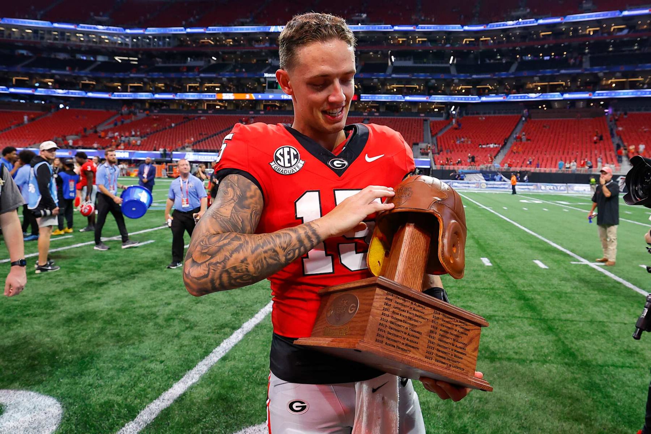ATHENS, GEORGIA - AUGUST 31: Carson Beck #15 of the Georgia Bulldogs holds the old leather helmet trophy following the 34-3 victory over the Clemson Tigers in the Aflac Kickoff Game at Mercedes-Benz Stadium on August 31, 2024 in Atlanta, Georgia.  (Photo by Todd Kirkland/Getty Images)