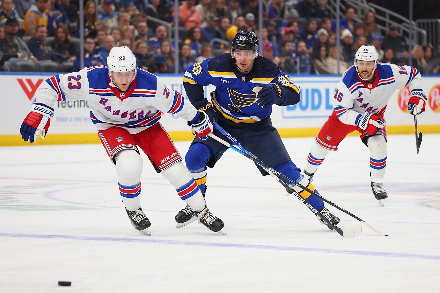 St. Louis Blues winger Pavel Buchnevich (center) races for the puck with New York Rangers defenseman Adam Fox.