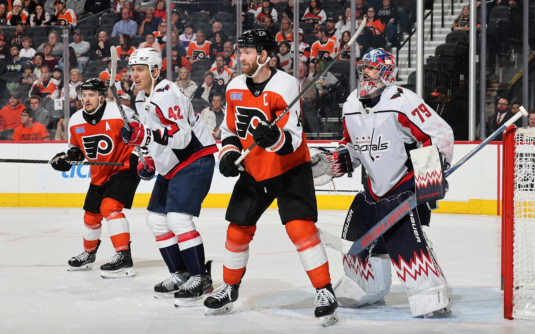 PHILADELPHIA, PENNSYLVANIA - APRIL 16:  Sean Couturier #14 and Travis Konecny #11 of the Philadelphia Flyers positioned on a scoring opportunity against Martin Fehervary #42 and Charlie Lindgren #79 of the Washington Capitals at the Wells Fargo Center on April 16, 2024 in Philadelphia, Pennsylvania.  (Photo by Len Redkoles/NHLI via Getty Images)