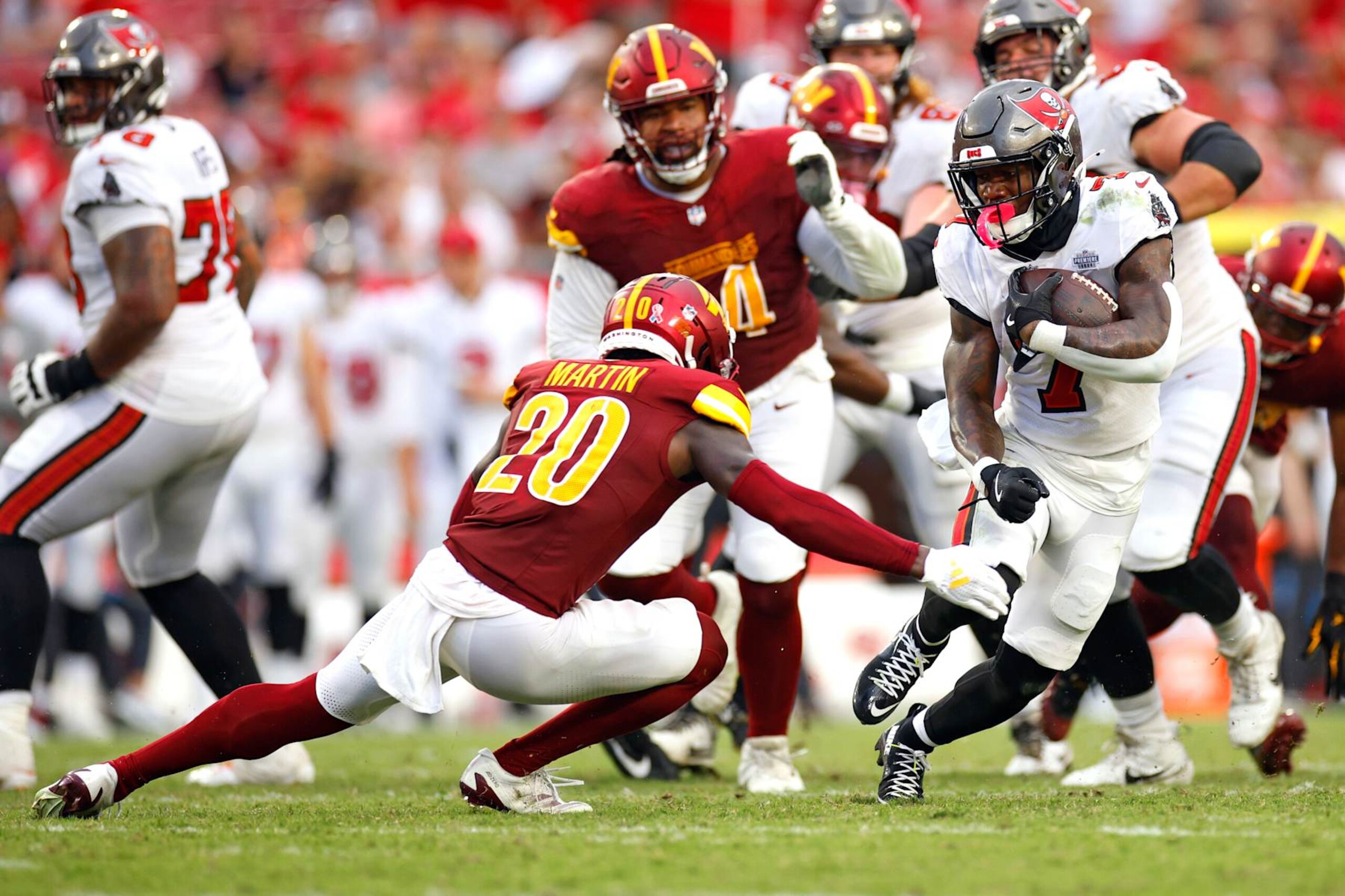 TAMPA, FLORIDA - SEPTEMBER 08: Bucky Irving #7 of the Tampa Bay Buccaneers carries the ball as he avoids a tackle by Quan Martin #20 of the Washington Commanders in the fourth quarter of the game at Raymond James Stadium on September 08, 2024 in Tampa, Florida. (Photo by Mike Ehrmann/Getty Images)