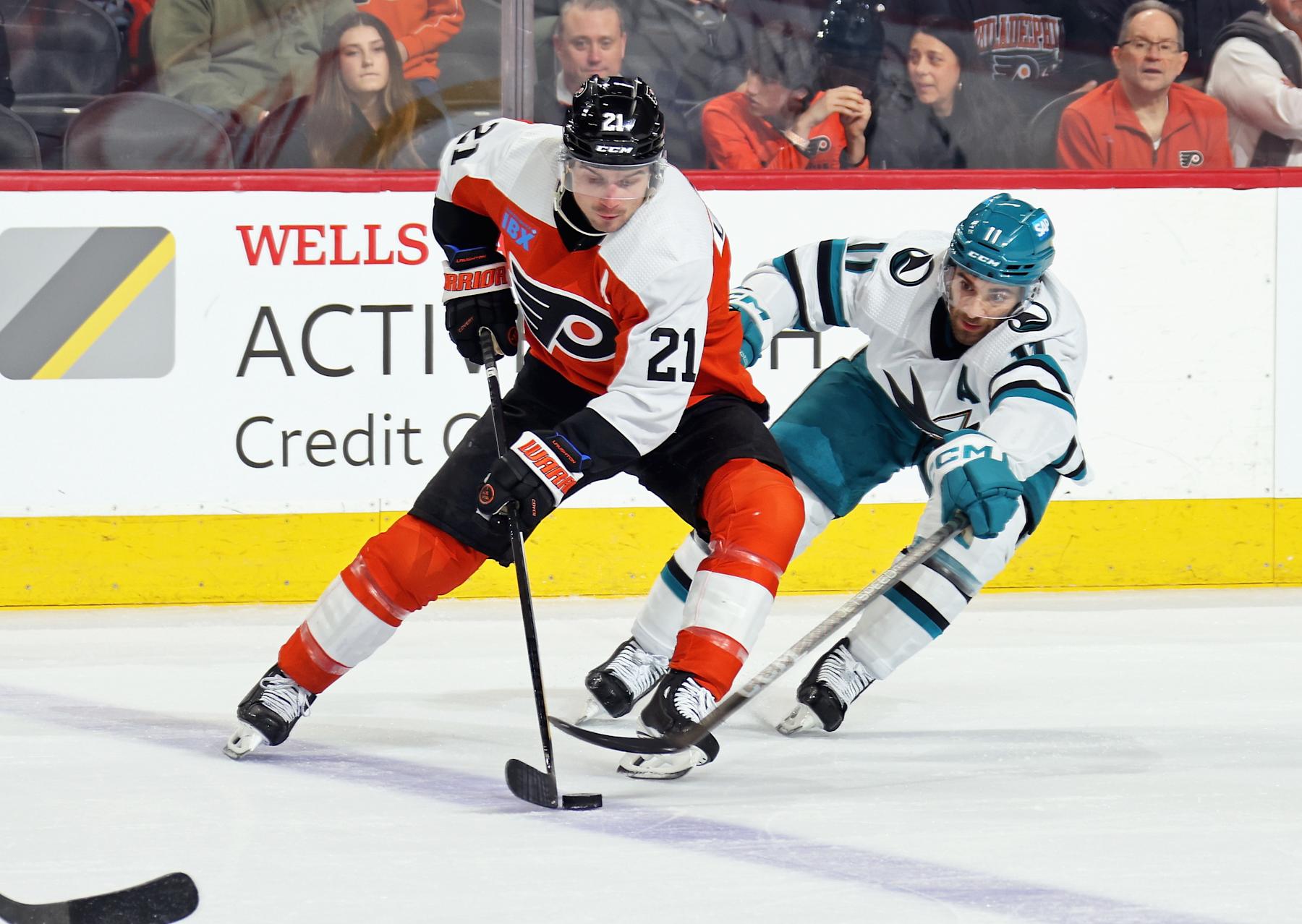 PHILADELPHIA, PENNSYLVANIA - MARCH 12:  Scott Laughton #21 of the Philadelphia Flyers skates the puck against Luke Kunin #11 of the San Jose Sharks at the Wells Fargo Center on March 12, 2024 in Philadelphia, Pennsylvania.  (Photo by Len Redkoles/NHLI via Getty Images)
