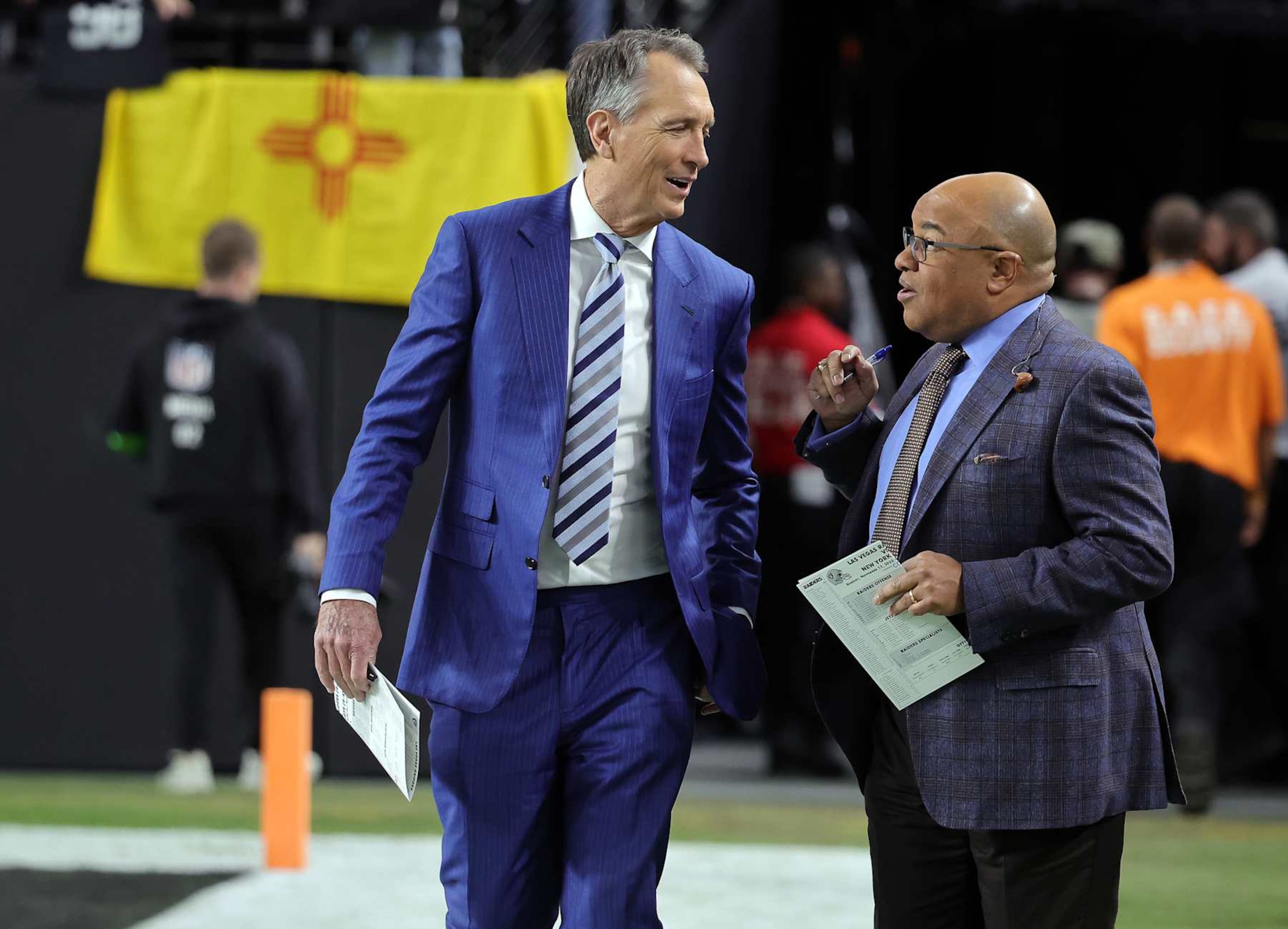 LAS VEGAS, NEVADA - NOVEMBER 12: NBC Sunday Night Football color commentator Cris Collinsworth (L) and play-by-play announcer Mike Tirico walk onto the field before a game between the New York Jets and the Las Vegas Raiders at Allegiant Stadium on November 12, 2023 in Las Vegas, Nevada. (Photo by Ethan Miller/Getty Images)