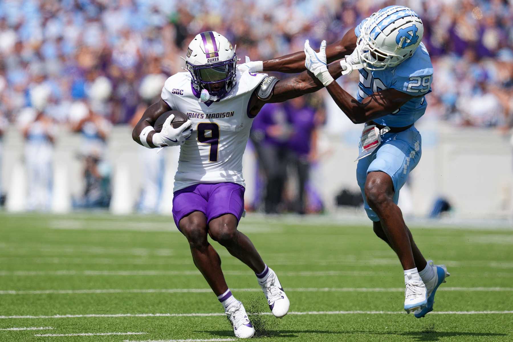 CHAPEL HILL, NORTH CAROLINA - SEPTEMBER 21: Omarion Dollison #9 of the James Madison Dukes stiff-arms Marcus Allen #29 of the North Carolina Tar Heels during the first half of the game at Kenan Memorial Stadium on September 21, 2024 in Chapel Hill, North Carolina.  (Photo by Grant Halverson/Getty Images)
