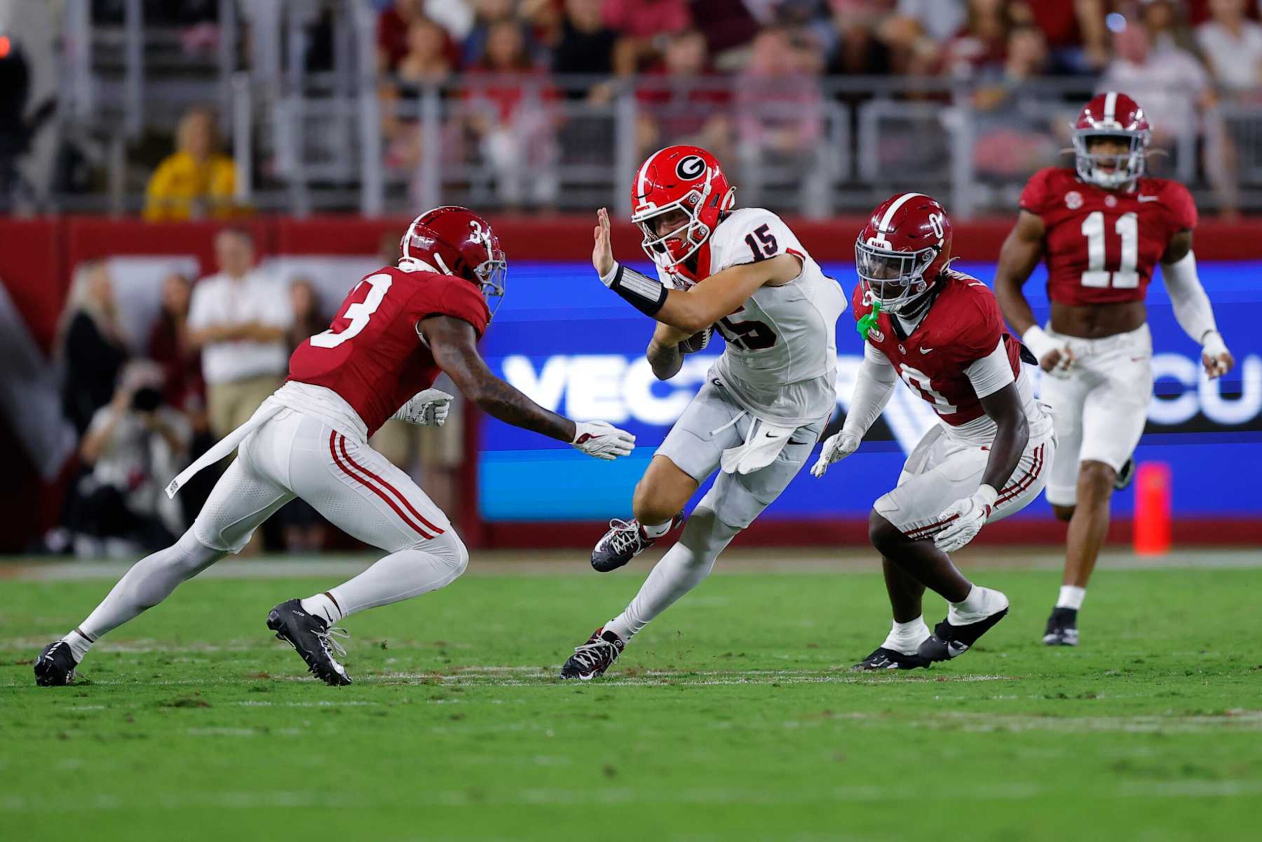 TUSCALOOSA, ALABAMA - SEPTEMBER 28: Carson Beck #15 of the Georgia Bulldogs carries the ball between Keon Sabb #3 and Deontae Lawson #0 of the Alabama Crimson Tide during the second quarter at Bryant-Denny Stadium on September 28, 2024 in Tuscaloosa, Alabama. (Photo by Todd Kirkland/Getty Images)