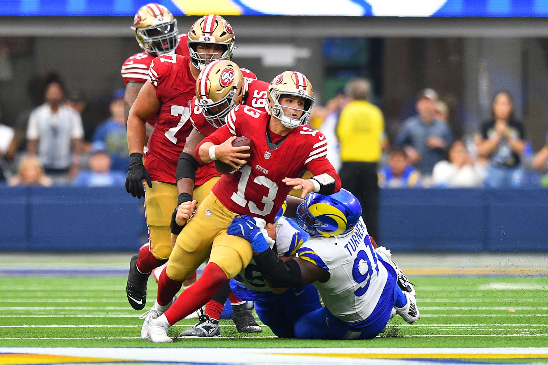 INGLEWOOD, CA - SEPTEMBER 22: San Francisco 49ers quarterback Brock Purdy (13) tries to escape pressure from Los Angeles Rams defensive tackle Kobie Turner (91) late in the NFL game between the San Francisco 49ers and the Los Angeles Rams on September 22, 2024, at SoFi Stadium in Inglewood, CA. (Photo by Brian Rothmuller/Icon Sportswire via Getty Images)