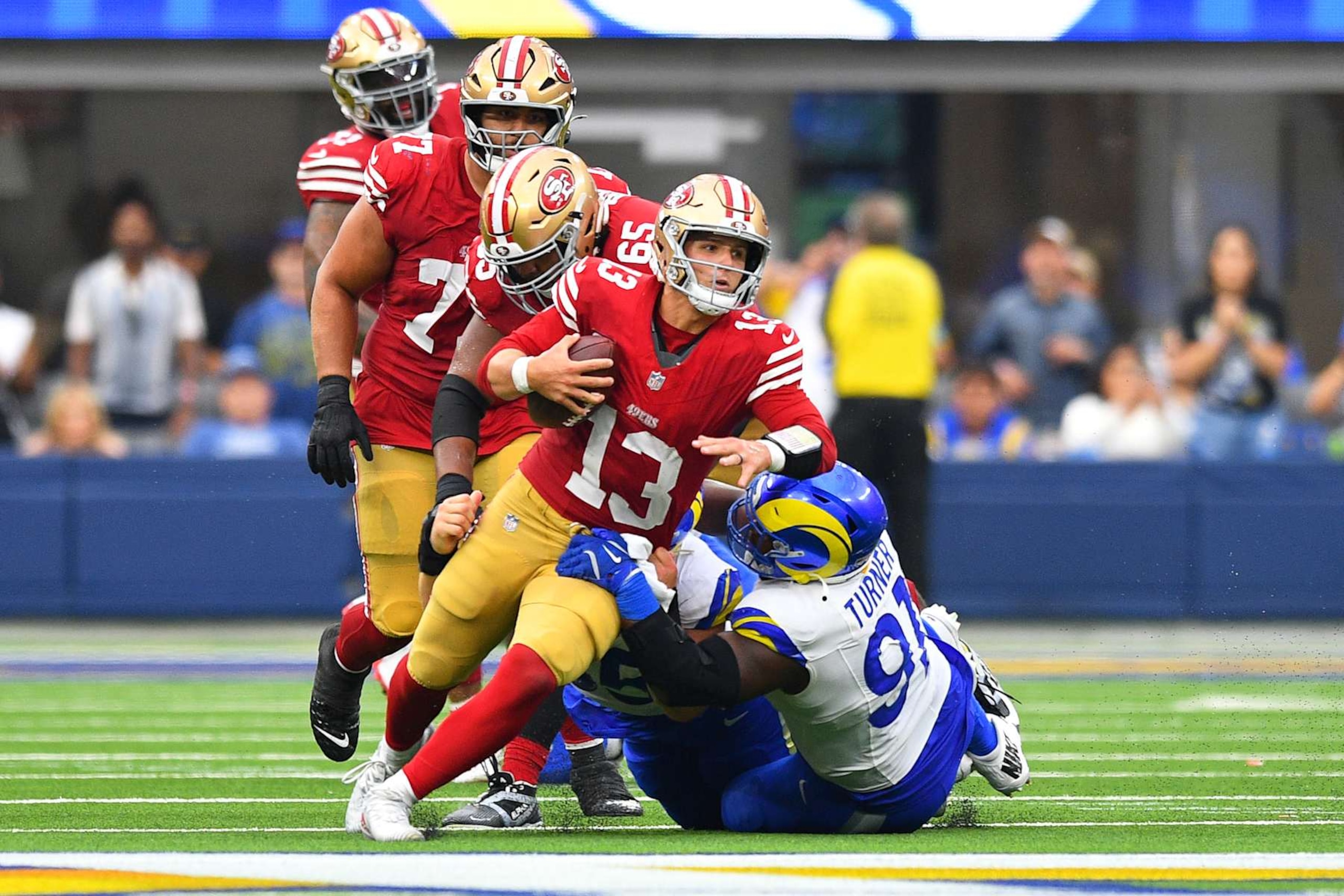 INGLEWOOD, CA - SEPTEMBER 22: San Francisco 49ers quarterback Brock Purdy (13) tries to escape pressure from Los Angeles Rams defensive tackle Kobie Turner (91) late in the NFL game between the San Francisco 49ers and the Los Angeles Rams on September 22, 2024, at SoFi Stadium in Inglewood, CA. (Photo by Brian Rothmuller/Icon Sportswire via Getty Images) INGLEWOOD, CA - SEPTEMBER 22: San Francisco 49ers quarterback Brock Purdy (13) tries to escape pressure from Los Angeles Rams defensive tackle Kobie Turner (91) late in the NFL game between the San Francisco 49ers and the Los Angeles Rams on September 22, 2024, at SoFi Stadium in Inglewood, CA. (Photo by Brian Rothmuller/Icon Sportswire via Getty Images)