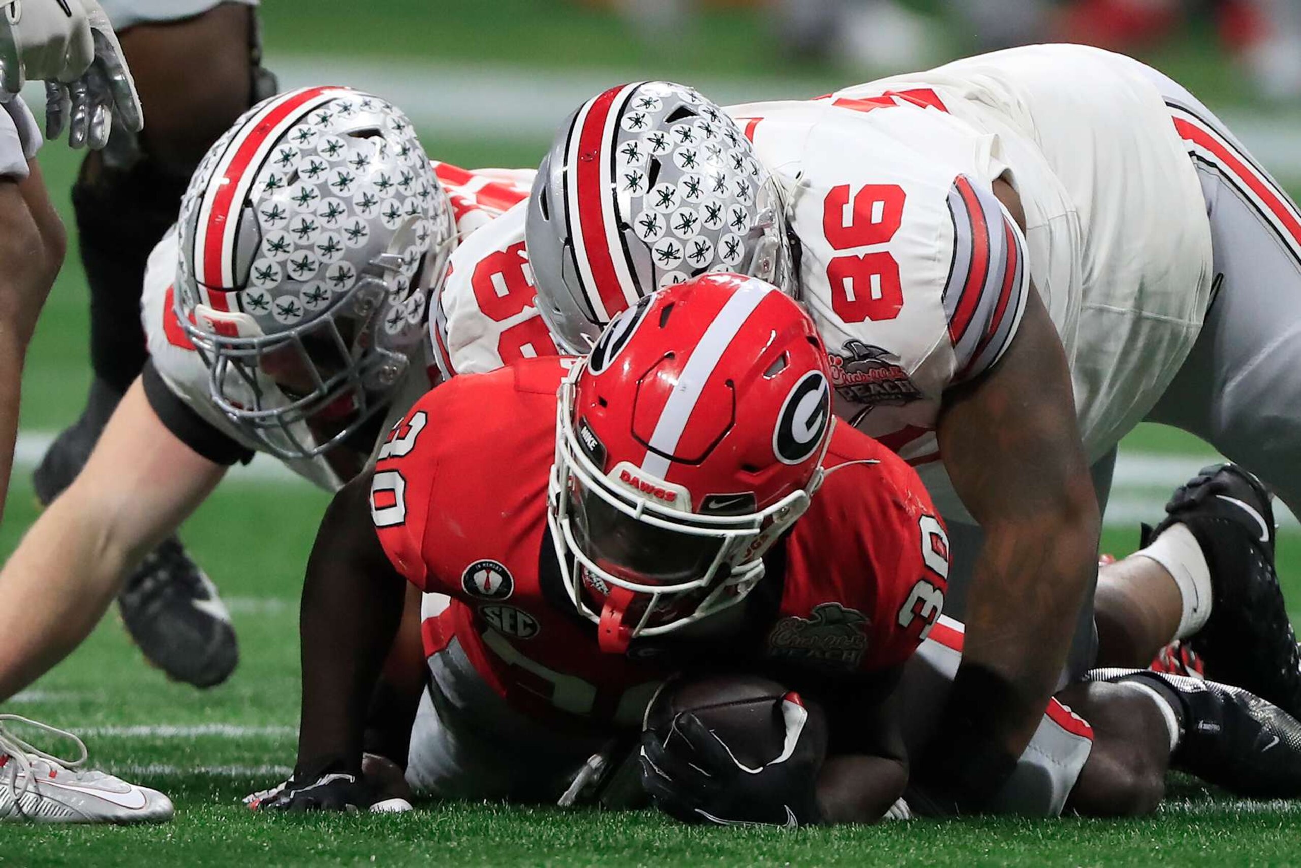ATLANTA, GA - DECEMBER 31: Ohio State Buckeyes place kicker Jake Seibert (98) and Ohio State Buckeyes defensive tackle Jerron Cage (86) bring down Georgia Bulldogs running back Daijun Edwards (30) during the college football playoff semifinal game between the University of Georgia Bulldogs and The Ohio State Buckeyes on December 31, 2022 at the Mercedes-Benz Stadium in Atlanta, GA.  (Photo by David J. Griffin/Icon Sportswire via Getty Images)