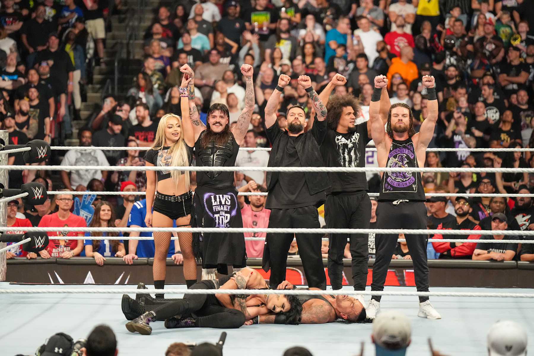 SUNRISE, FLORIDA - AUGUST 19: Liv Morgan, Dominik Mysterio, Finn Balor, JD McDonagh, and Carlito of the Judgment Day stand over Rhea Ripley and Damian Priest during Monday Night RAW at Amerant Bank Arena on August 19, 2024 in Sunrise, Florida.  (Photo by WWE/Getty Images)