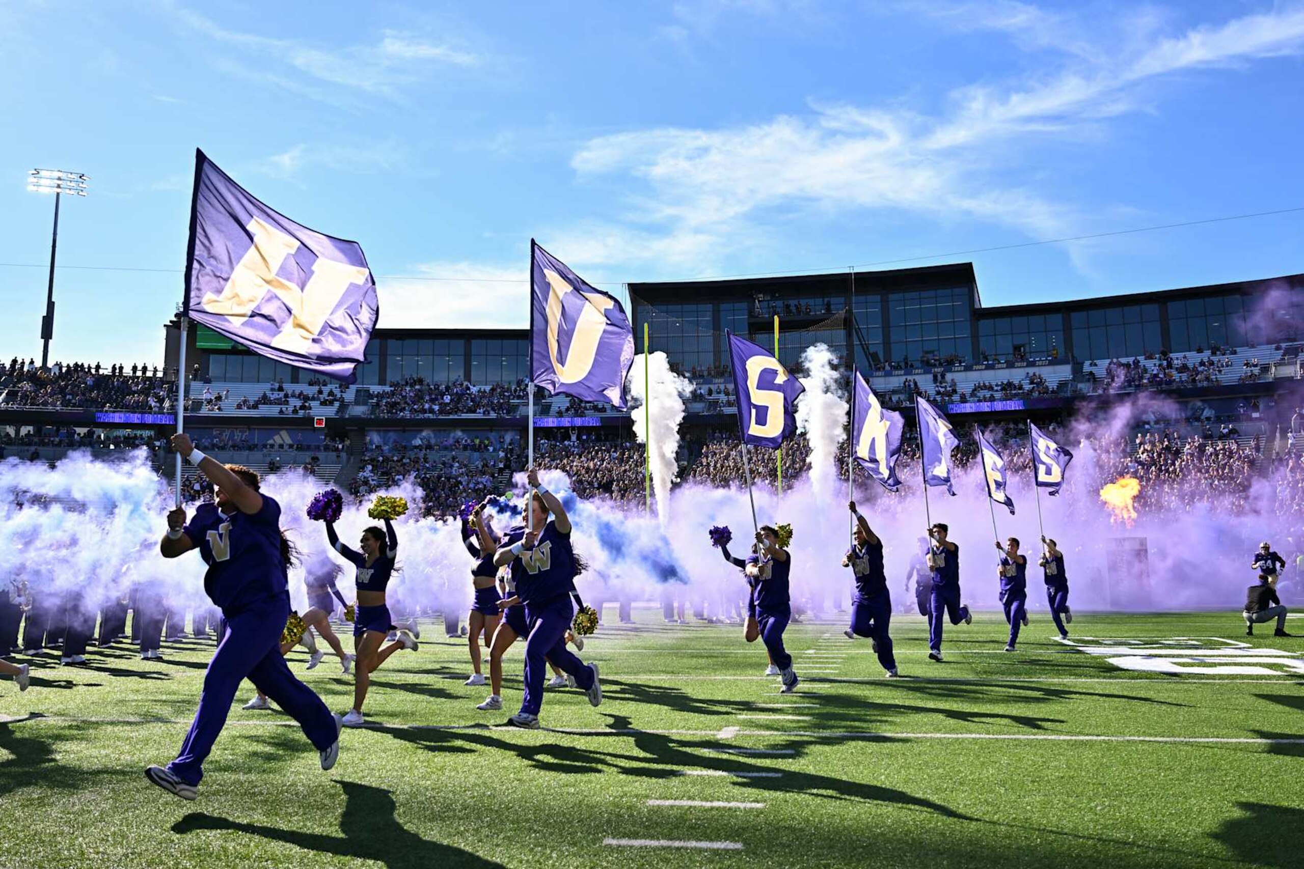 SEATTLE, WASHINGTON - SEPTEMBER 21: The Washington Huskies spirit team run the field holding flags before the game against the Northwestern Wildcats at Husky Stadium on September 21, 2024 in Seattle, Washington. The Huskies defeated the Wildcats 24-5. (Photo by Alika Jenner/Getty Images)