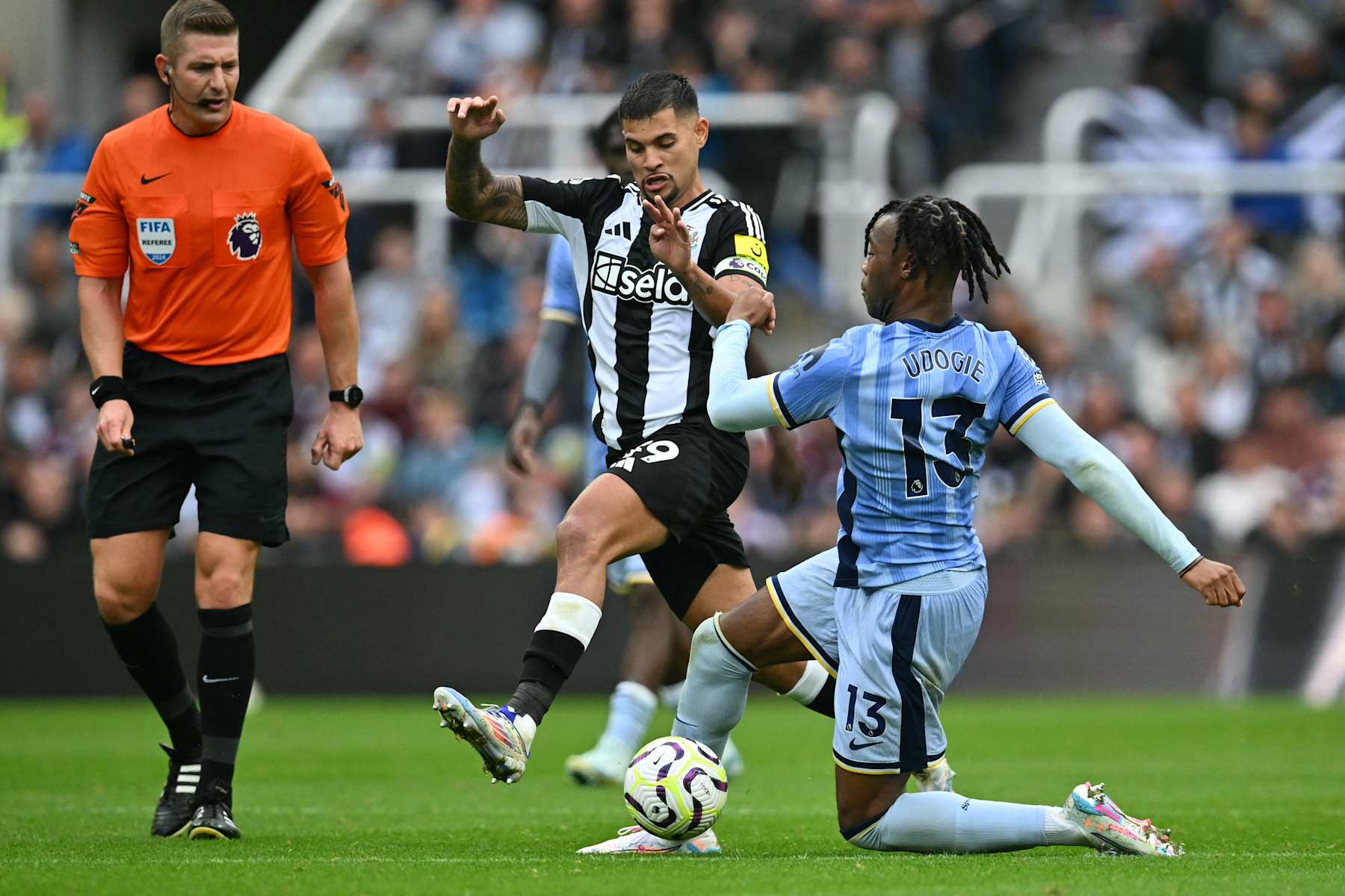 Tottenham Hotspur's Italian defender #13 Destiny Udogie (R) vies with Newcastle United's Brazilian midfielder #39 Bruno Guimaraes (C) during the English Premier League football match between Newcastle United and Tottenham Hotspur at St James' Park in Newcastle-upon-Tyne, north east England on September 1, 2024. (Photo by ANDY BUCHANAN / AFP) / RESTRICTED TO EDITORIAL USE. No use with unauthorized audio, video, data, fixture lists, club/league logos or 'live' services. Online in-match use limited to 120 images. An additional 40 images may be used in extra time. No video emulation. Social media in-match use limited to 120 images. An additional 40 images may be used in extra time. No use in betting publications, games or single club/league/player publications. /  (Photo by ANDY BUCHANAN/AFP via Getty Images)
