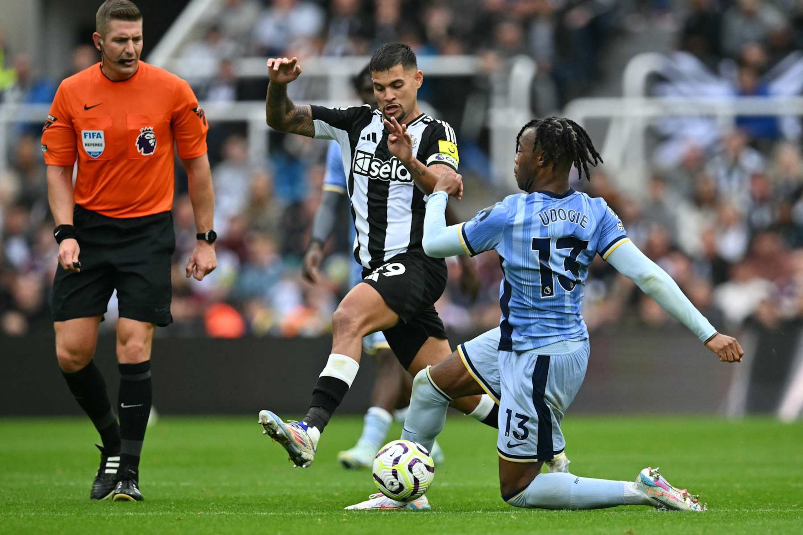 Tottenham Hotspur's Italian defender #13 Destiny Udogie (R) vies with Newcastle United's Brazilian midfielder #39 Bruno Guimaraes (C) during the English Premier League football match between Newcastle United and Tottenham Hotspur at St James' Park in Newcastle-upon-Tyne, north east England on September 1, 2024. (Photo by ANDY BUCHANAN / AFP) / RESTRICTED TO EDITORIAL USE. No use with unauthorized audio, video, data, fixture lists, club/league logos or 'live' services. Online in-match use limited to 120 images. An additional 40 images may be used in extra time. No video emulation. Social media in-match use limited to 120 images. An additional 40 images may be used in extra time. No use in betting publications, games or single club/league/player publications. /  (Photo by ANDY BUCHANAN/AFP via Getty Images)