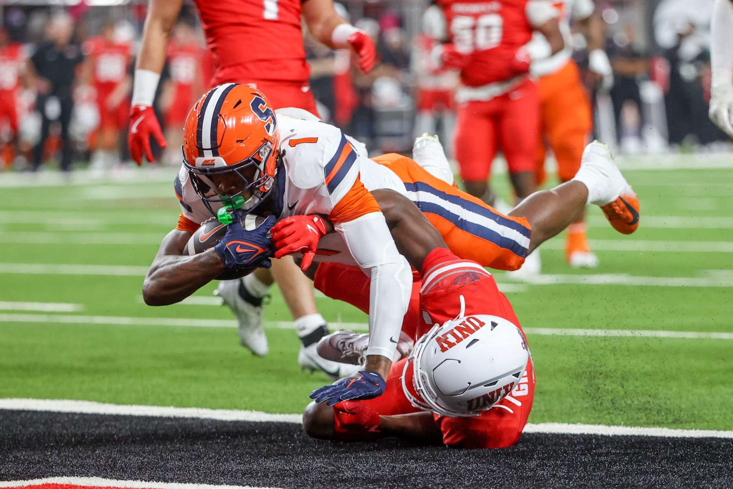 LAS VEGAS, NEVADA - OCTOBER 04: LeQuint Allen #1 of the Syracuse Orange runs over Tony Grimes #0 of the UNLV Rebels while scoring a rushing touchdown during the first quarter of a game at Allegiant Stadium on October 04, 2024 in Las Vegas, Nevada. (Photo by Ian Maule/Getty Images)