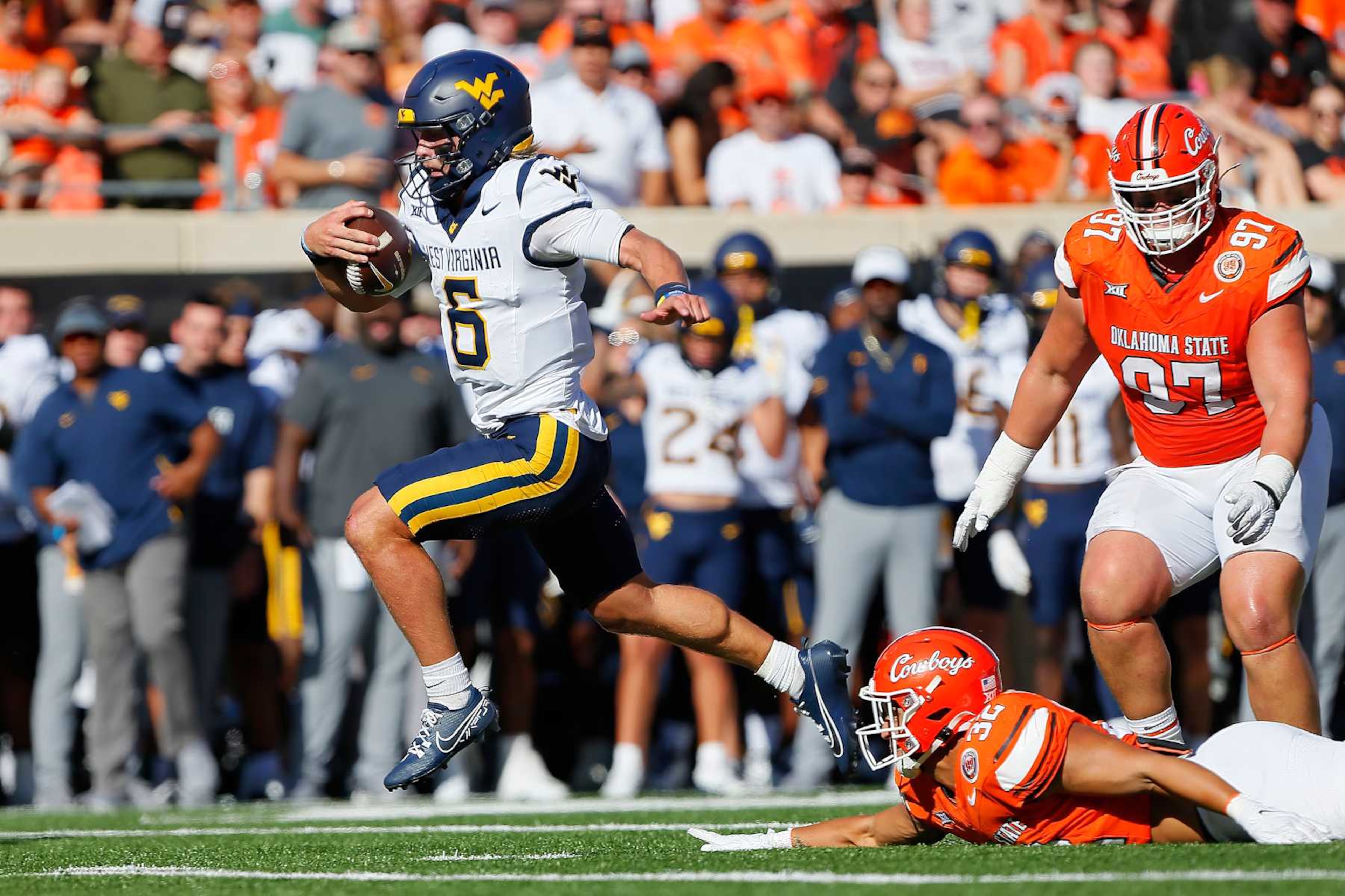STILLWATER, OK - OCTOBER 5: Quarterback Garrett Greene #6 of the West Virginia Mountaineers escapes the grasp of linebacker Gabe Brown #32 of the Oklahoma State Cowboys to score a 15-yard touchdown in the second quarter at Boone Pickens Stadium on October 5, 2024 in Stillwater, Oklahoma. (Photo by Brian Bahr/Getty Images) STILLWATER, OK - OCTOBER 5: Quarterback Garrett Greene #6 of the West Virginia Mountaineers escapes the grasp of linebacker Gabe Brown #32 of the Oklahoma State Cowboys to score a 15-yard touchdown in the second quarter at Boone Pickens Stadium on October 5, 2024 in Stillwater, Oklahoma. (Photo by Brian Bahr/Getty Images)