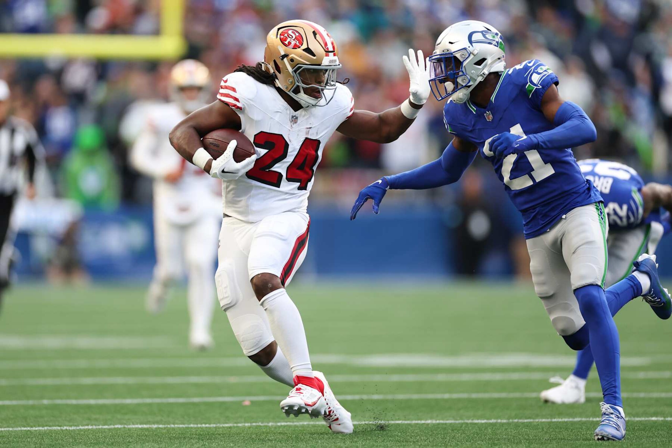 SEATTLE, WASHINGTON - OCTOBER 10: Jordan Mason #24 of the San Francisco 49ers runs the ball against Devon Witherspoon #21 of the Seattle Seahawks during the first quarter at Lumen Field on October 10, 2024 in Seattle, Washington. (Photo by Steph Chambers/Getty Images)