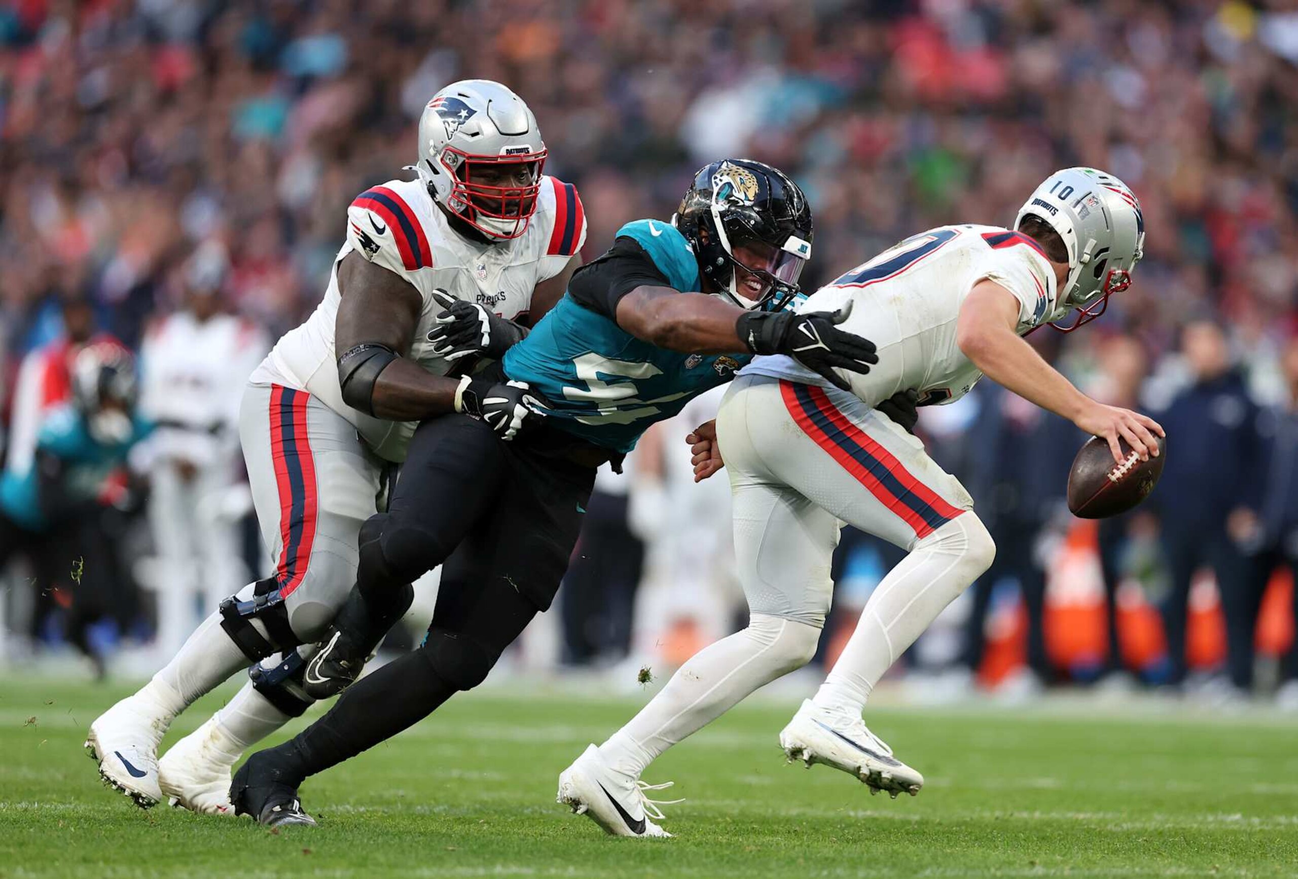 LONDON, ENGLAND - OCTOBER 20: Drake Maye of New England Patriots is challenged by Travon Walker of Jacksonville Jaguars during the NFL match between New England Patriots and Jacksonville Jaguars at Wembley Stadium on October 20, 2024 in London, England. (Photo by Julian Finney/Getty Images)