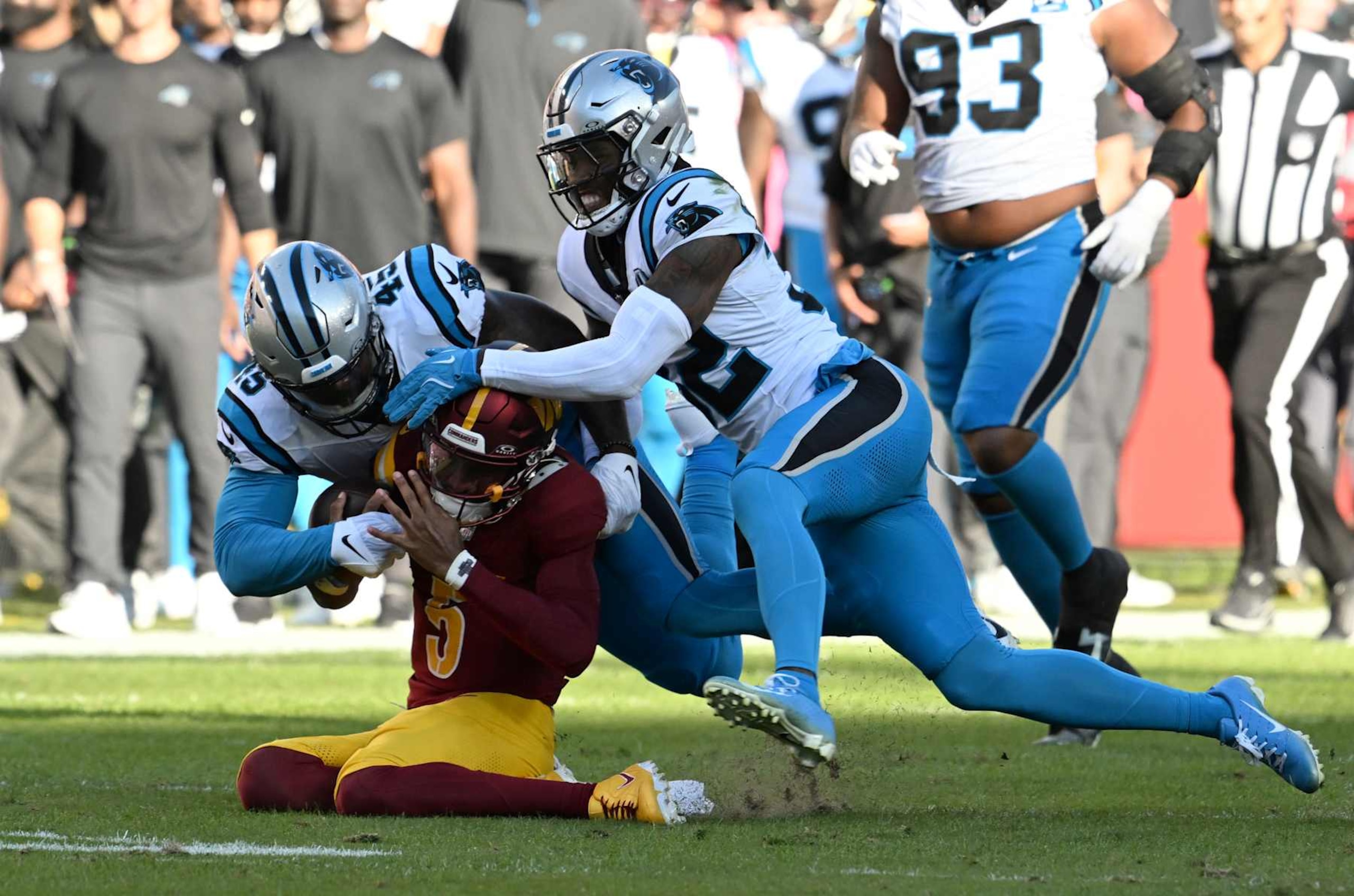 LANDOVER, MARYLAND - OCTOBER 20: Jayden Daniels #5 of the Washington Commanders is tackled by Marquis Haynes #45 and Lonnie Johnson Jr. #32 of the Carolina Panthers during the first quarter at Northwest Stadium on October 20, 2024 in Landover, Maryland. (Photo by Greg Fiume/Getty Images)