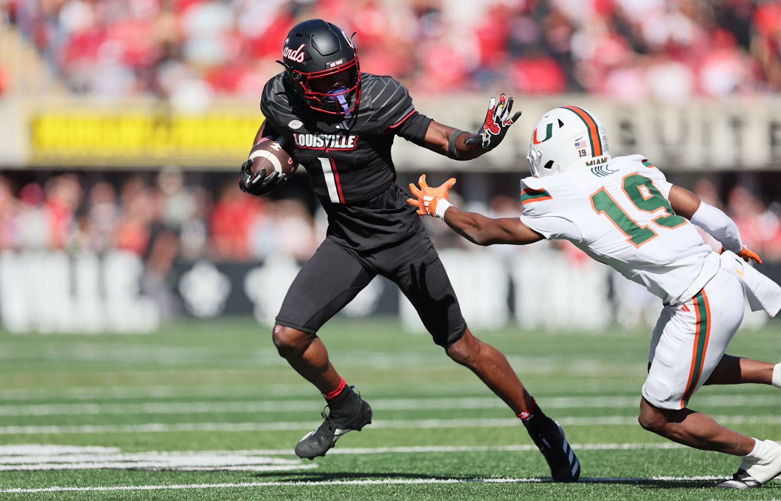 LOUISVILLE, KENTUCKY - OCTOBER 19: Ja"Corey Brooks #1 of the Louisville Cardinals runs with the ball while defended by Ny Carr #19 of the Miami Hurricanes at Cardinal Stadium on October 19, 2024 in Louisville, Kentucky. (Photo by Andy Lyons/Getty Images)