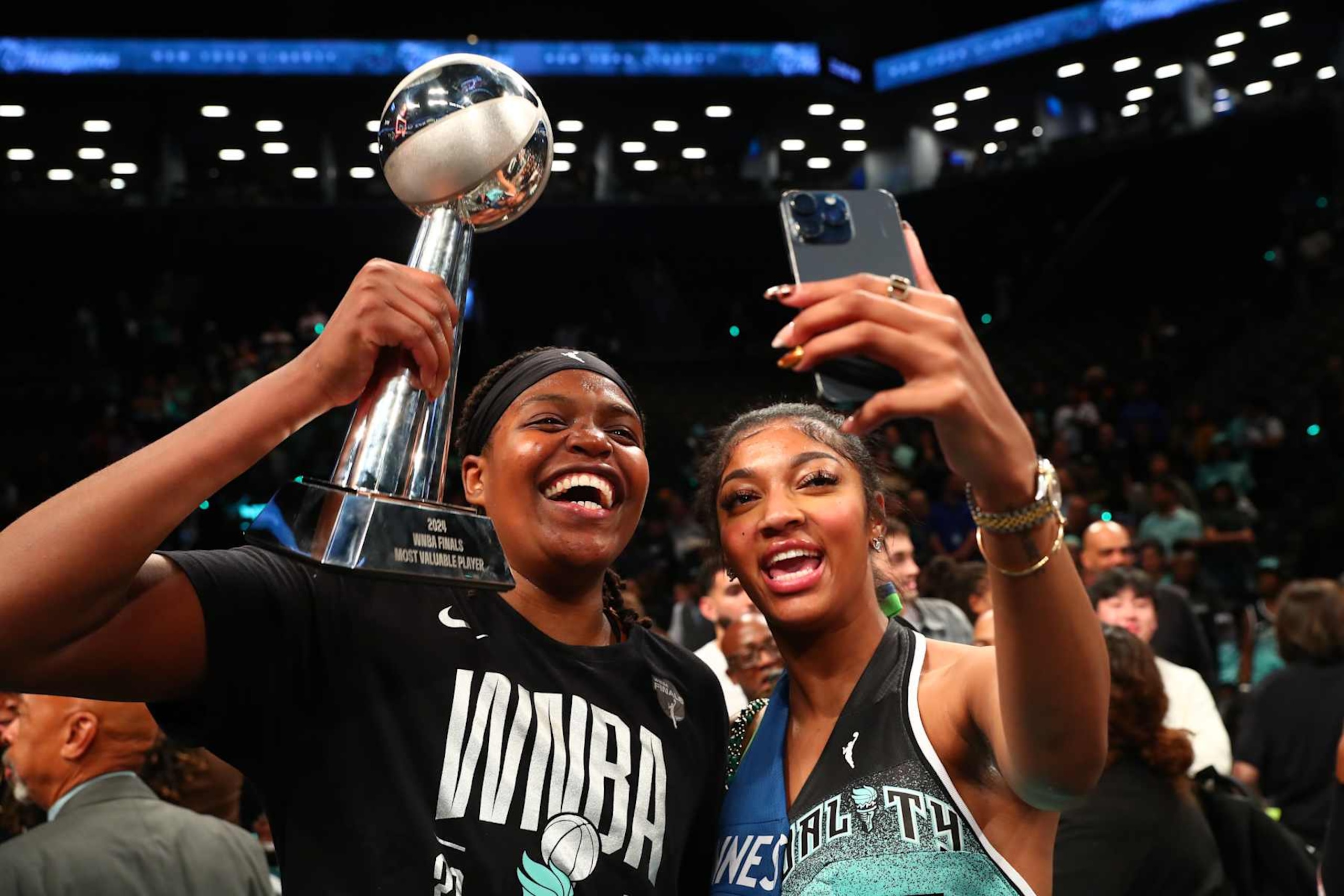 BROOKLYN, NY - OCTOBER 20: Jonquel Jones #35 of the New York Liberty and Angel Reese celebrate with the 2024 WNBA Finals MVP trophy after defeating the Minnesota Lynx during Game Five of the 2024 WNBA Finals on October 20, 2024 in Brooklyn, New York. NOTE TO USER: User expressly acknowledges and agrees that, by downloading and or using this photograph, user is consenting to the terms and conditions of the Getty Images License Agreement. Mandatory Copyright Notice: Copyright 2024 NBAE (Photo by David L. Nemec/NBAE via Getty Images)