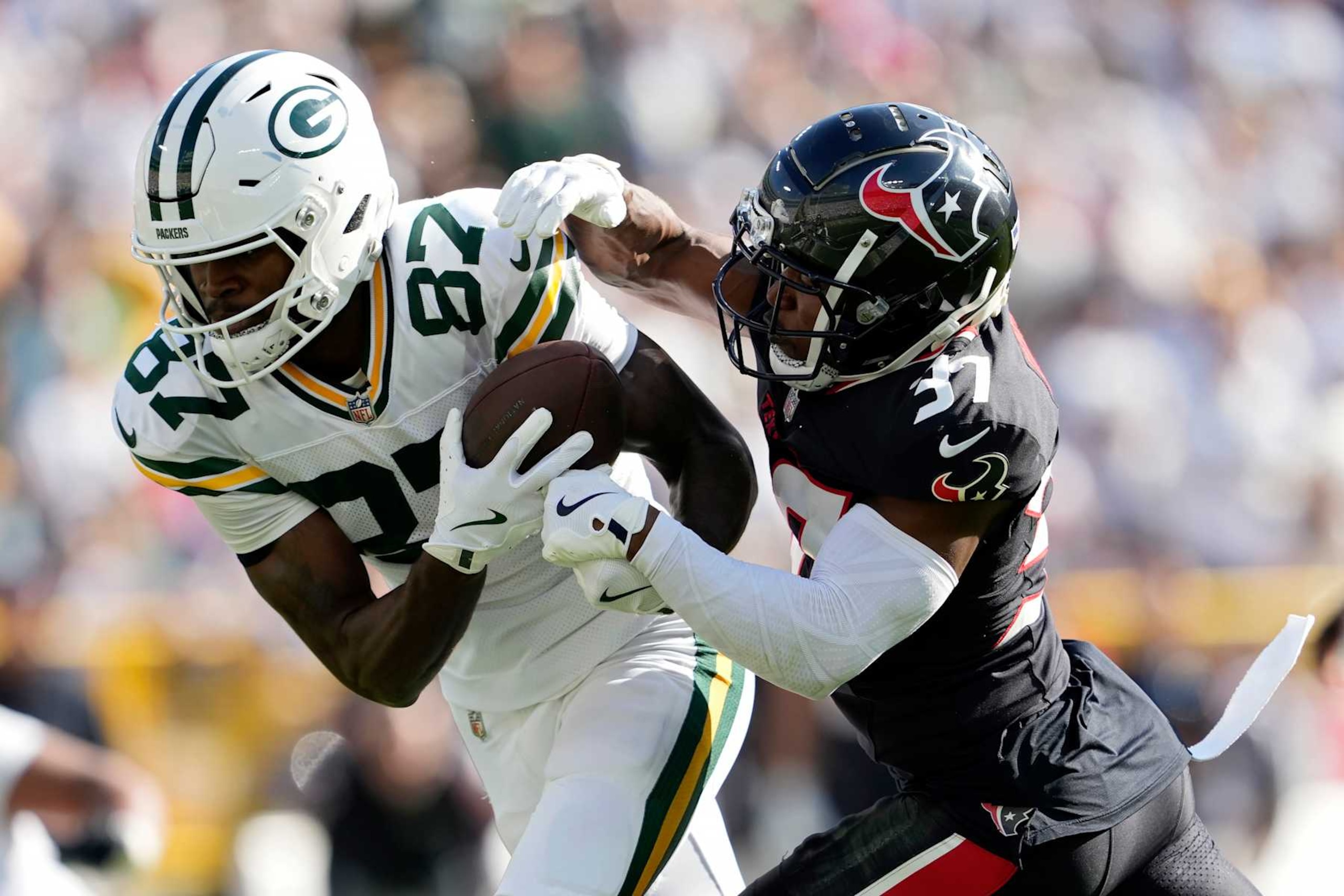 GREEN BAY, WISCONSIN - OCTOBER 20: Romeo Doubs #87 of the Green Bay Packers catches a pass in front of D'Angelo Ross #37 of the Houston Texans during the third quarter at Lambeau Field on October 20, 2024 in Green Bay, Wisconsin. (Photo by Patrick McDermott/Getty Images)