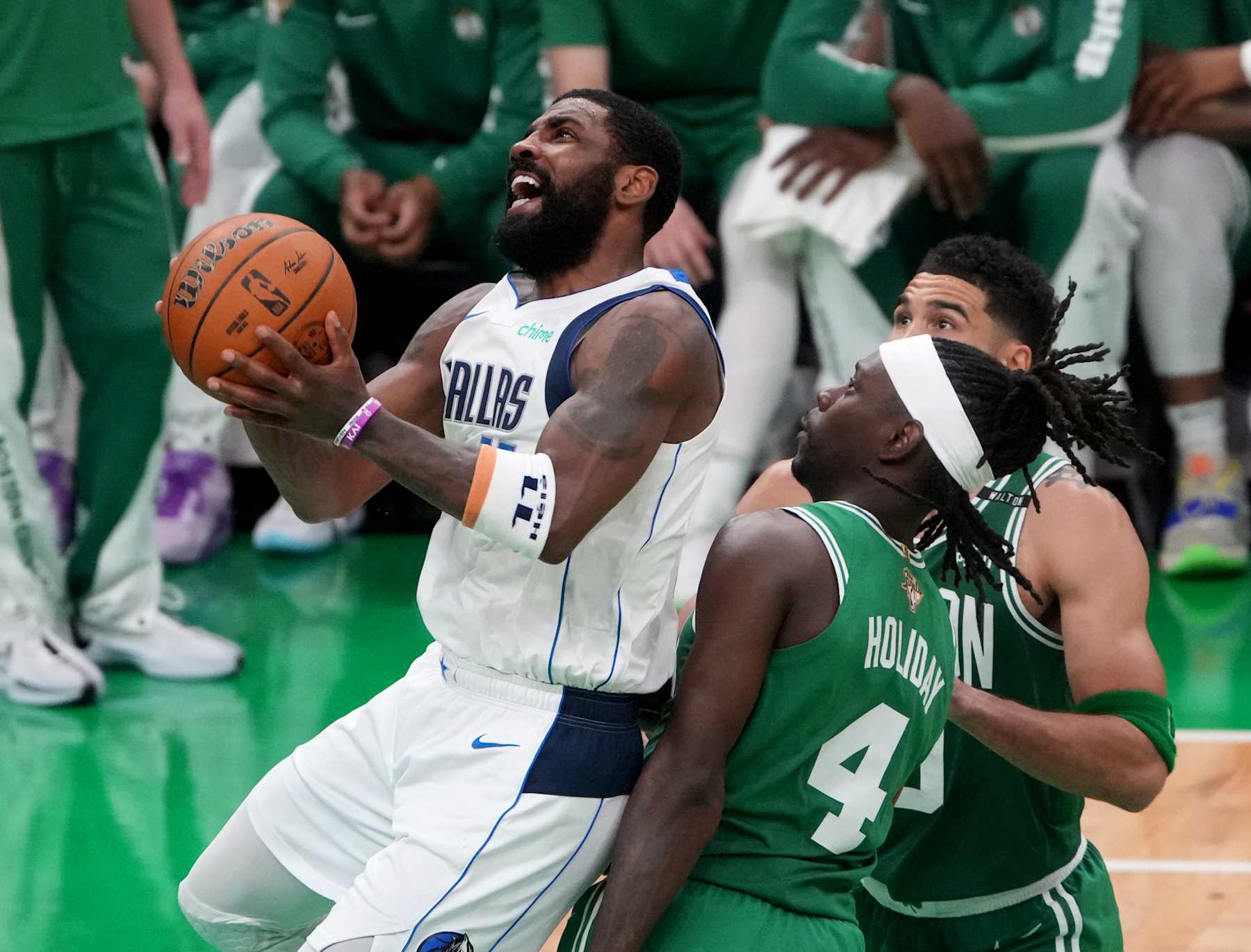 Boston, MA - June 17: Dallas Mavericks guard Kyrie Irving drives to the basket against Boston Celtics guard Jrue Holiday  and forward Jayson Tatum during the second quarter in Game 5 of the 2024 NBA Finals. (Photo by Barry Chin/The Boston Globe via Getty Images)