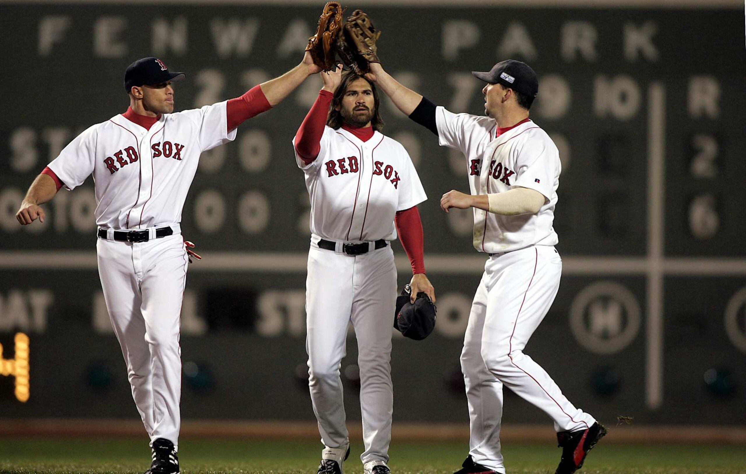 BOSTON - OCTOBER 24: With the final score visible behind them, Boston Red Sox outfielders Gabe Kapler, Johnny Damon, and Trot Nixon celebrate the Game Two victory.(Photo by Jim Davis/The Boston Globe via Getty Images)