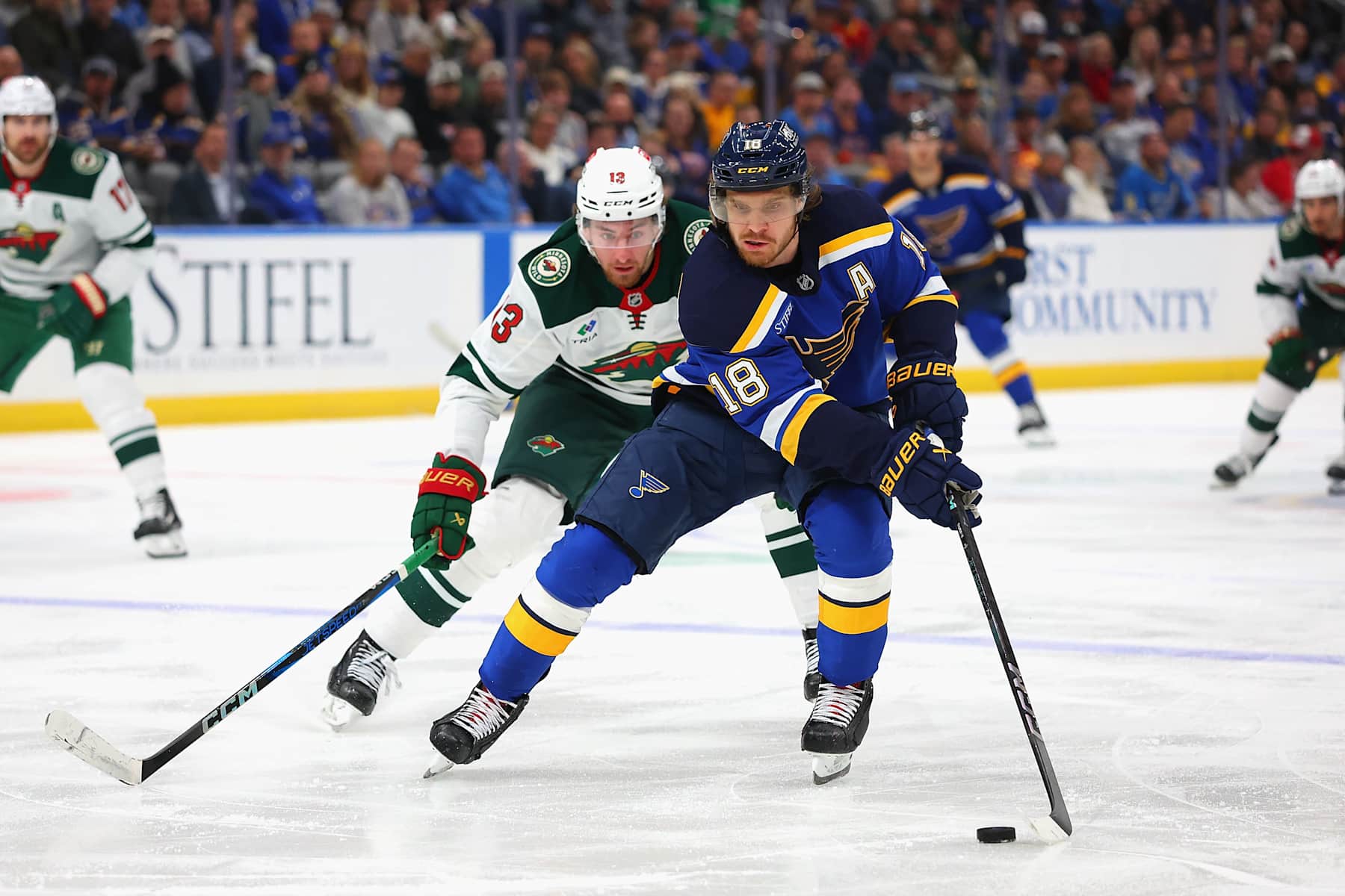 ST LOUIS, MISSOURI - OCTOBER 15: Robert Thomas #18 of the St. Louis Blues controls the puck against Yakov Trenin #13 of the Minnesota Wild in the third period at Enterprise Center on October 15, 2024 in St Louis, Missouri. (Photo by Dilip Vishwanat/Getty Images)