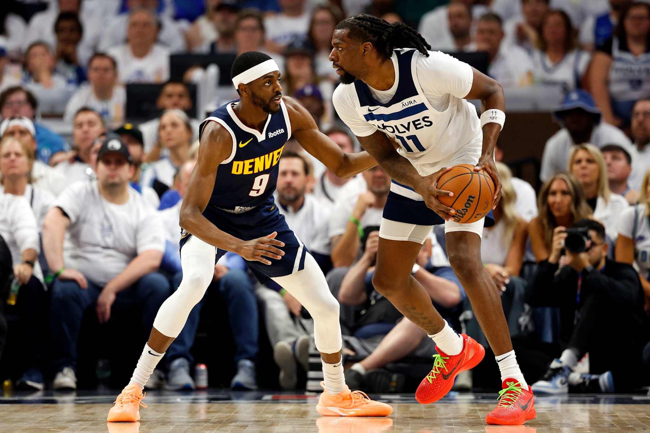 MINNEAPOLIS, MINNESOTA - MAY 12: Naz Reid #11 of the Minnesota Timberwolves handles the ball against Justin Holiday #9 of the Denver Nuggets in the third quarter of Game Four of the Western Conference Second Round Playoffs at Target Center on May 12, 2024 in Minneapolis, Minnesota. The Nuggets defeated the Timberwolves 115-107. (Photo by David Berding/Getty Images)