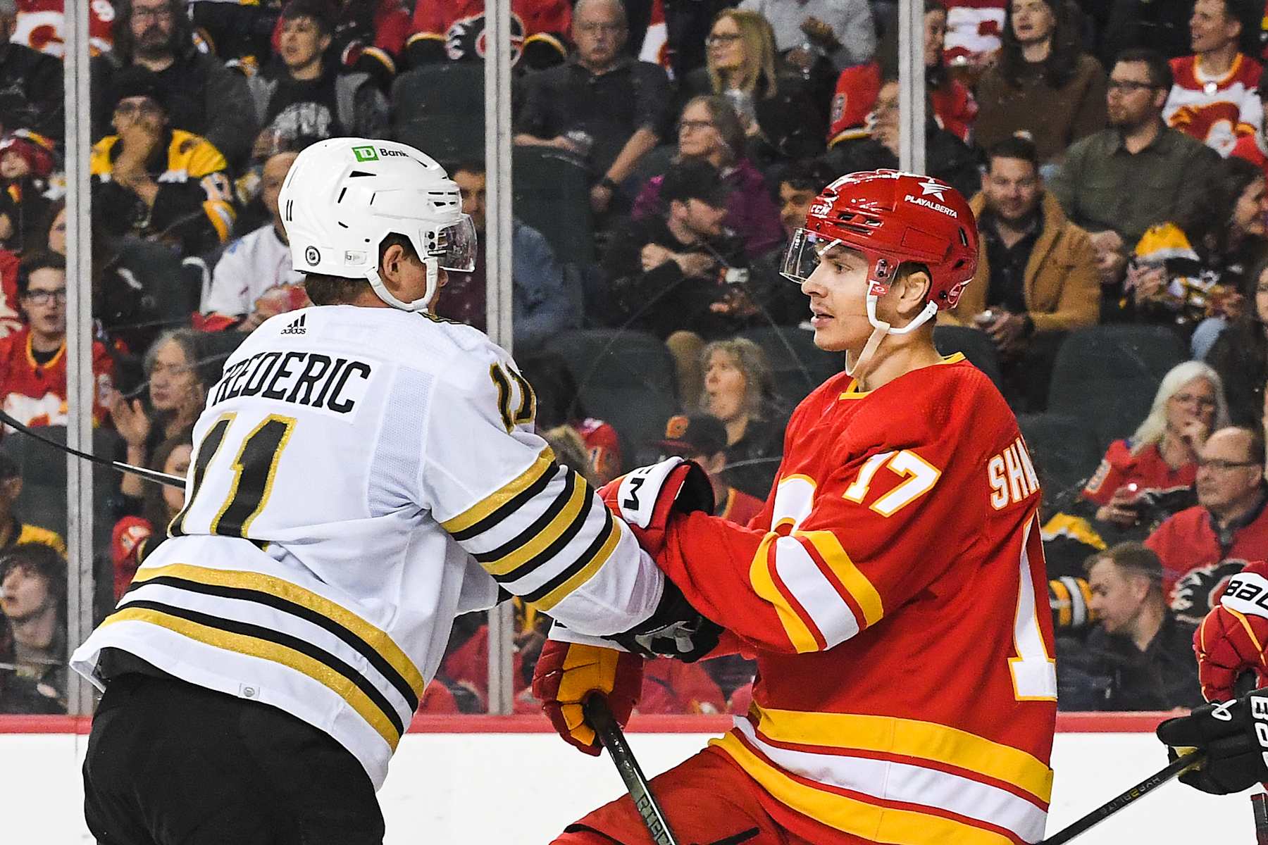 CALGARY, CANADA - FEBRUARY 22: Yegor Sharangovich #17 of the Calgary Flames shoves Trent Frederic #11 of the Boston Bruins after the whistle during the third period of an NHL game at Scotiabank Saddledome on February 22, 2024 in Calgary, Alberta, Canada. The Flames defeated the Bruins 3-2 in overtime. (Photo by Derek Leung/Getty Images)