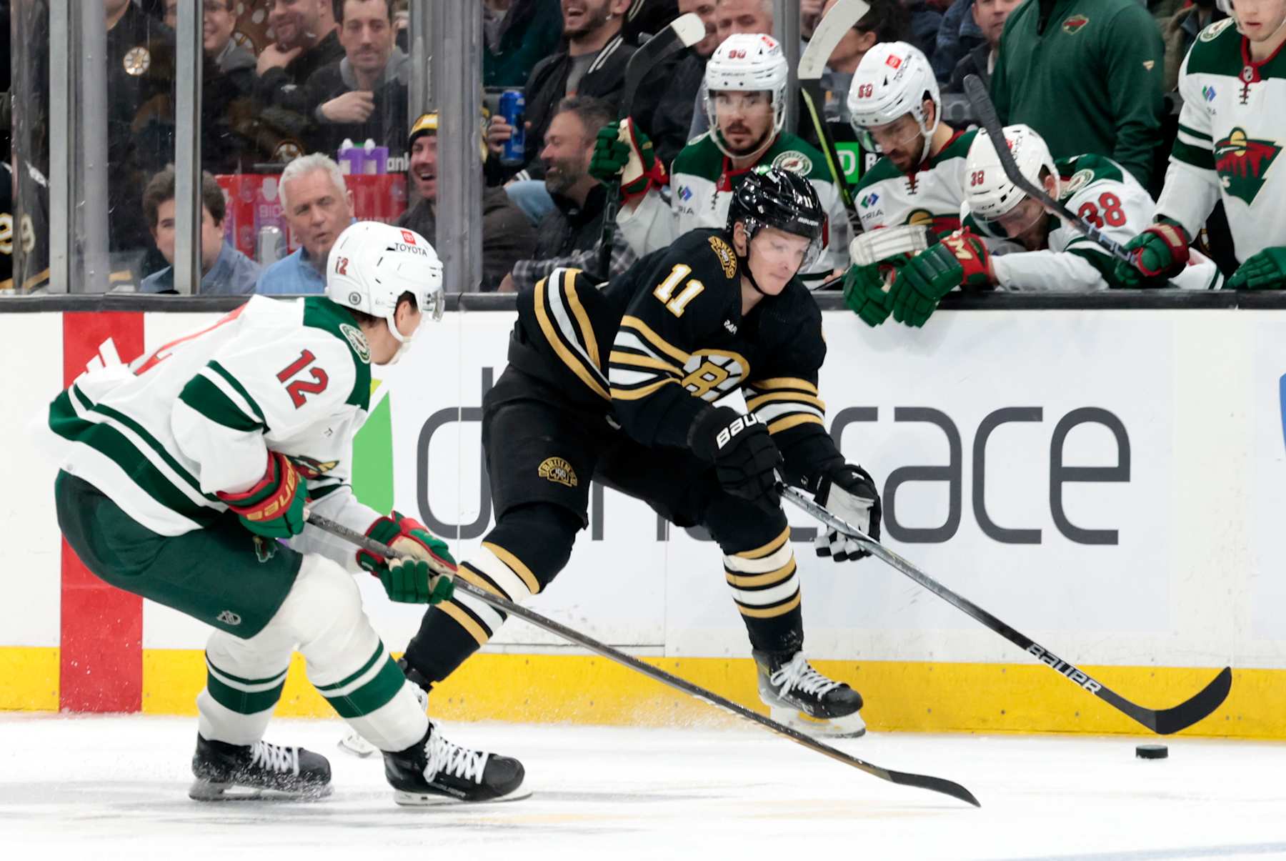 BOSTON, MA - DECEMBER 19: Boston Bruins center Trent Frederic (11) watched by Minnesota Wild right wing Matt Boldy (12) during a game between the Boston Bruins and the Minnesota Wild on December 19, 2023, at TD Garden in Boston, Massachusetts. (Photo by Fred Kfoury III/Icon Sportswire via Getty Images)