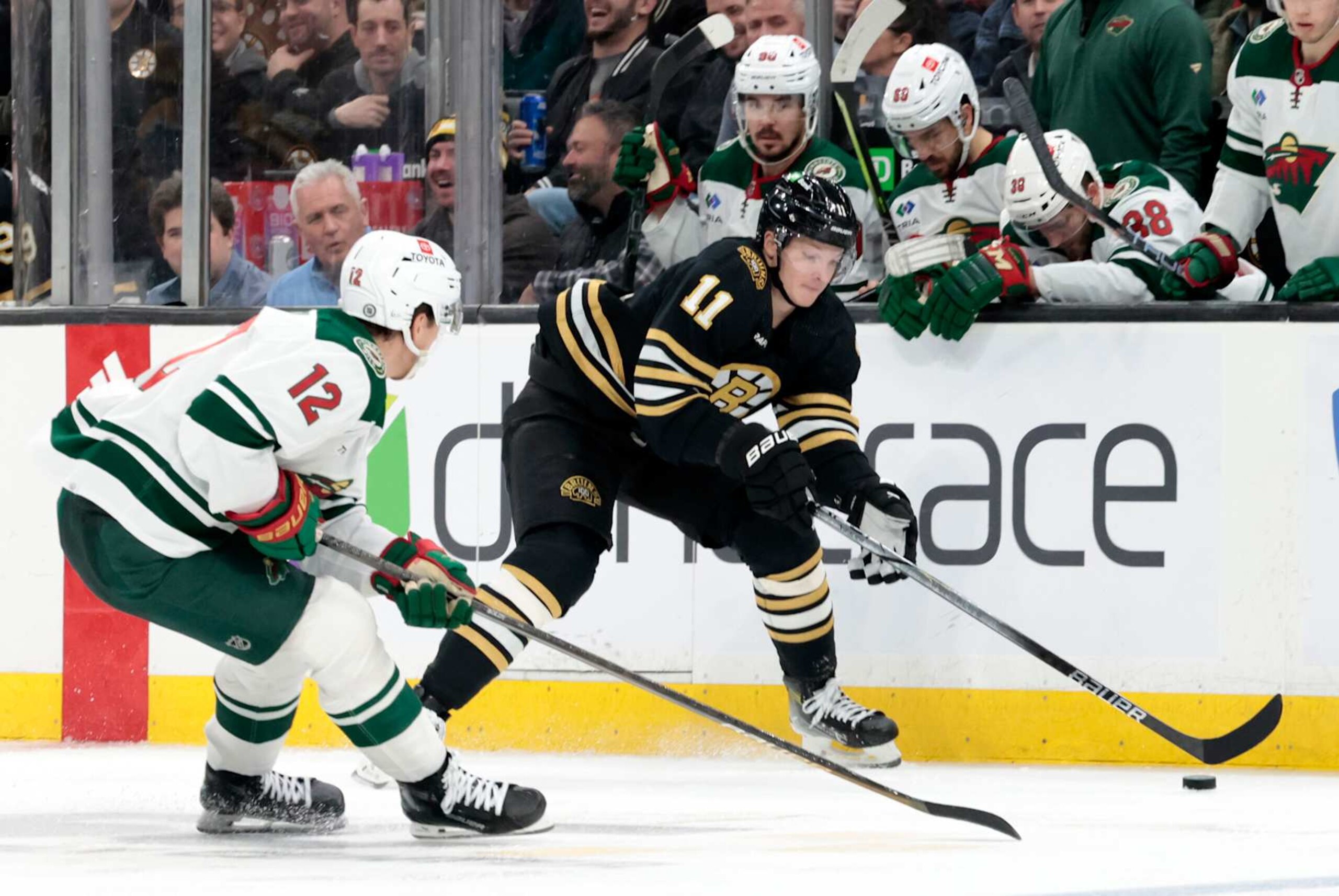 BOSTON, MA - DECEMBER 19: Boston Bruins center Trent Frederic (11) watched by Minnesota Wild right wing Matt Boldy (12) during a game between the Boston Bruins and the Minnesota Wild on December 19, 2023, at TD Garden in Boston, Massachusetts. (Photo by Fred Kfoury III/Icon Sportswire via Getty Images) BOSTON, MA - DECEMBER 19: Boston Bruins center Trent Frederic (11) watched by Minnesota Wild right wing Matt Boldy (12) during a game between the Boston Bruins and the Minnesota Wild on December 19, 2023, at TD Garden in Boston, Massachusetts. (Photo by Fred Kfoury III/Icon Sportswire via Getty Images)