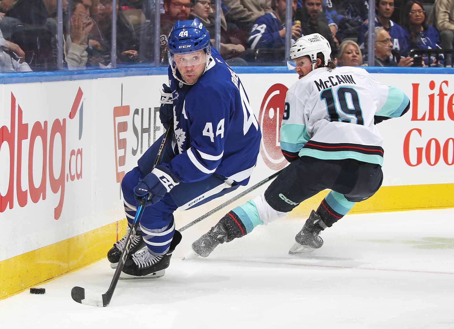 TORONTO, CANADA - OCTOBER 31:  Morgan Rielly #44 of the Toronto Maple Leafs skates away with the puck against Jared McCann #19 of the Seattle Kraken during the Third period in an NHL game at Scotiabank Arena on October 31, 2024 in Toronto, Ontario, Canada. The Maple Leafs defeated the Kraken 4-1. (Photo by Claus Andersen/Getty Images)