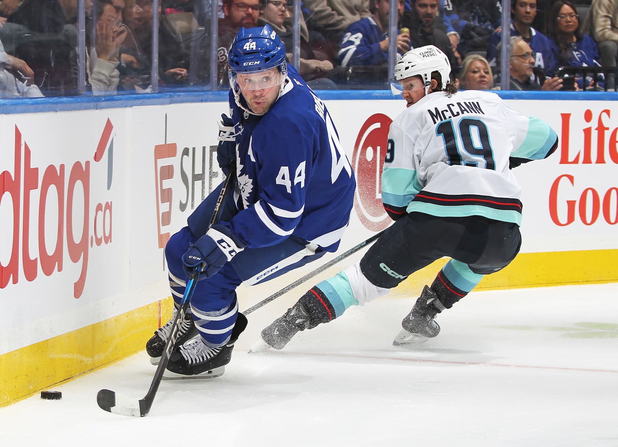 TORONTO, CANADA - OCTOBER 31:  Morgan Rielly #44 of the Toronto Maple Leafs skates away with the puck against Jared McCann #19 of the Seattle Kraken during the Third period in an NHL game at Scotiabank Arena on October 31, 2024 in Toronto, Ontario, Canada. The Maple Leafs defeated the Kraken 4-1. (Photo by Claus Andersen/Getty Images)