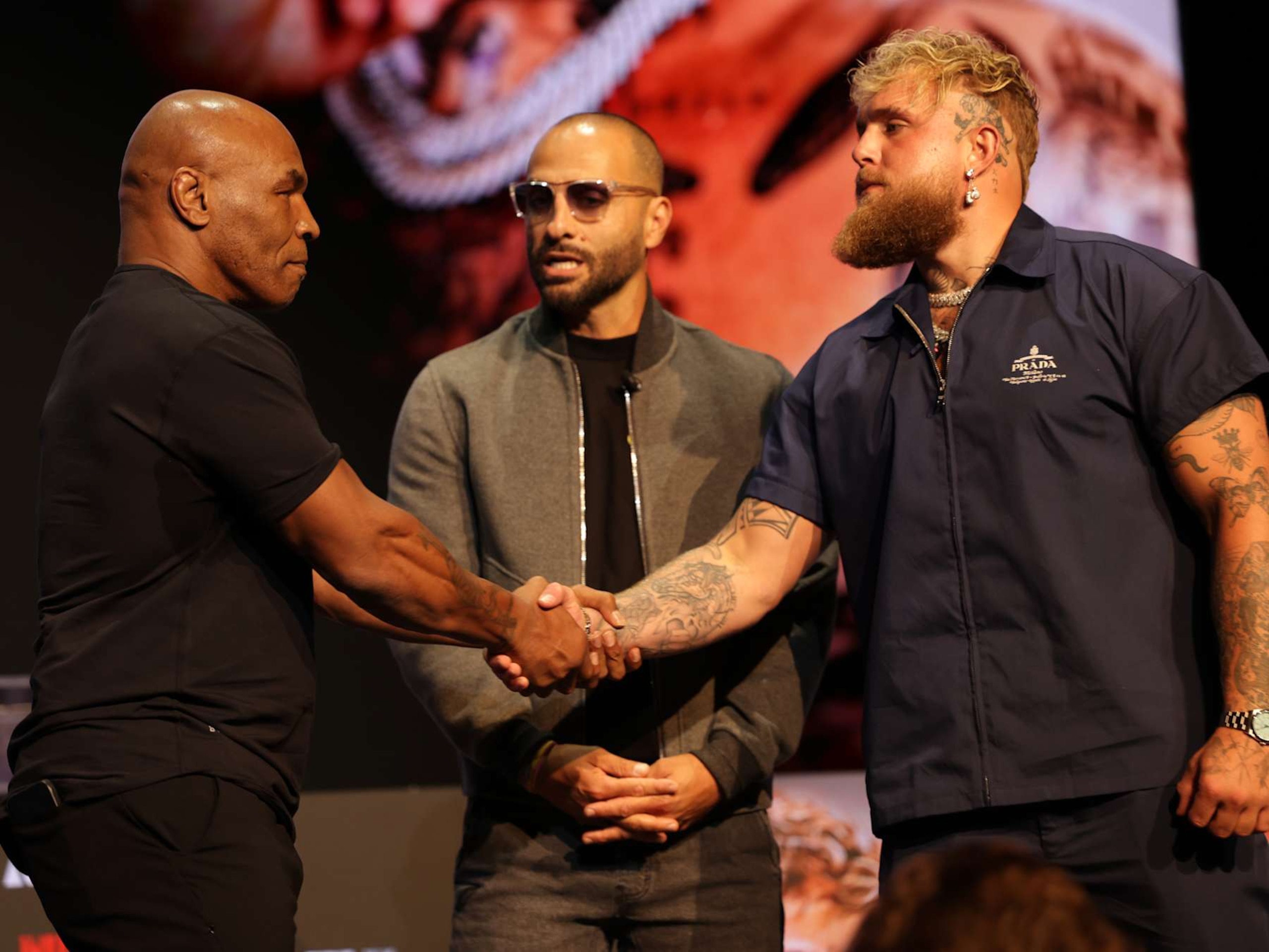 Mike Tyson and Jake Paul shake hands at a pre-fight press conference.