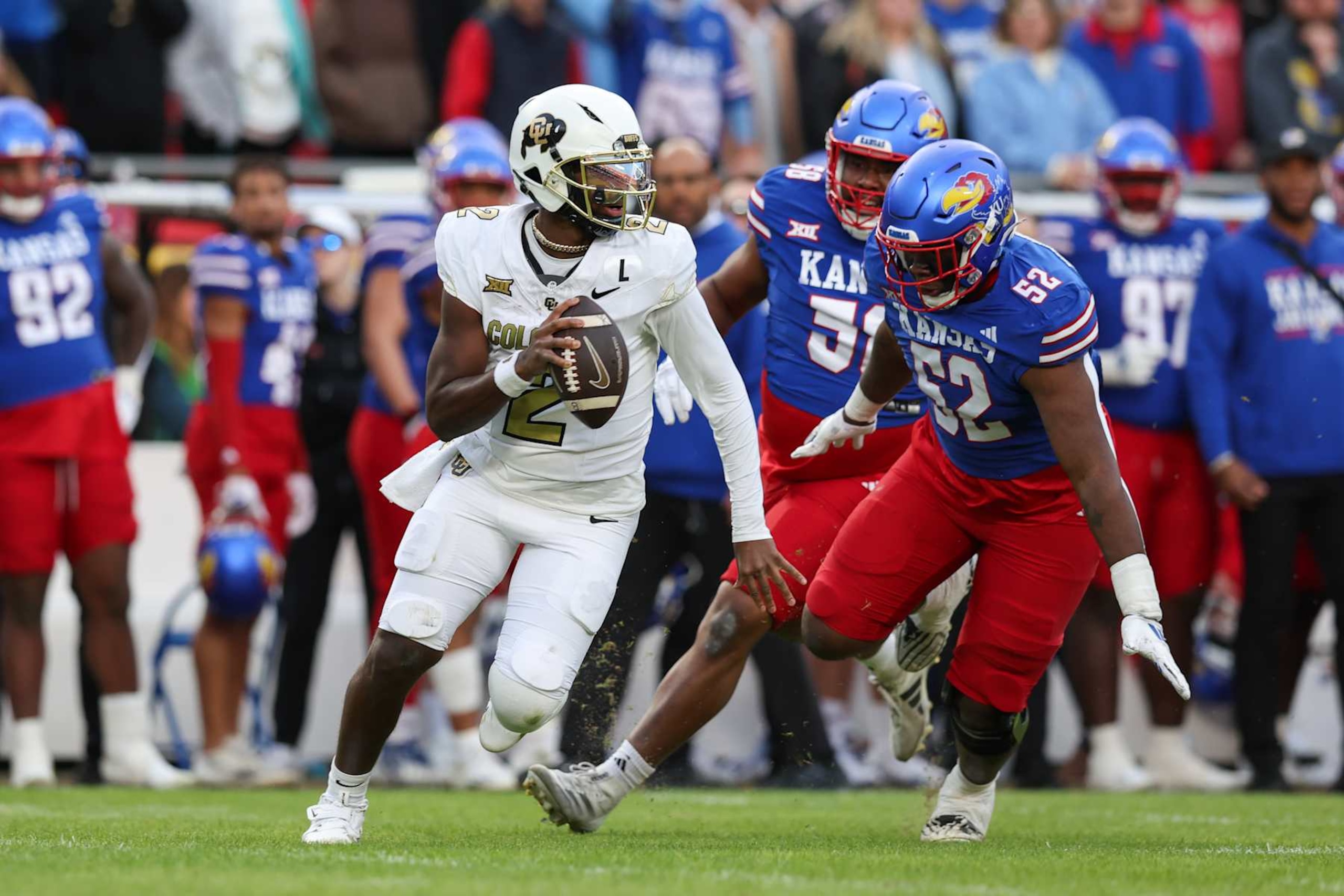 KANSAS CITY, MO - NOVEMBER 23: Colorado Buffaloes quarterback Shedeur Sanders (2) scrambles away from the pressure o fKansas Jayhawks defensive tackle D.J. Withers (52) in the second quarter of a Big 12 game between the Colorado Buffaloes and Kansas Jayhawks on November 23, 2024 at GEHA Field at Arrowhead Stadium in Kansas City, MO. (Photo by Scott Winters/Icon Sportswire via Getty Images) KANSAS CITY, MO - NOVEMBER 23: Colorado Buffaloes quarterback Shedeur Sanders (2) scrambles away from the pressure o fKansas Jayhawks defensive tackle D.J. Withers (52) in the second quarter of a Big 12 game between the Colorado Buffaloes and Kansas Jayhawks on November 23, 2024 at GEHA Field at Arrowhead Stadium in Kansas City, MO. (Photo by Scott Winters/Icon Sportswire via Getty Images)