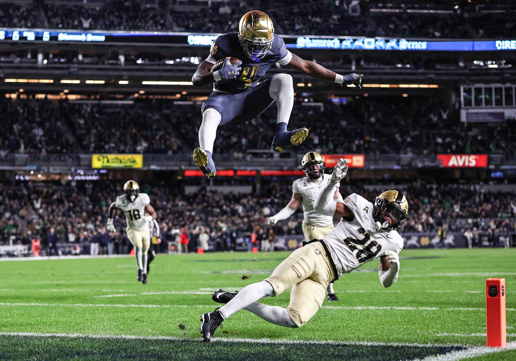 NEW YORK, NEW YORK - NOVEMBER 23: Jeremiyah Love #4 of the Notre Dame Fighting Irish hurdles over Donavon Platt #28 of the Army Black Knights to score a touchdown during the first quarter of the game at Yankee Stadium on November 23, 2024 in New York City. (Photo by Dustin Satloff/Getty Images)