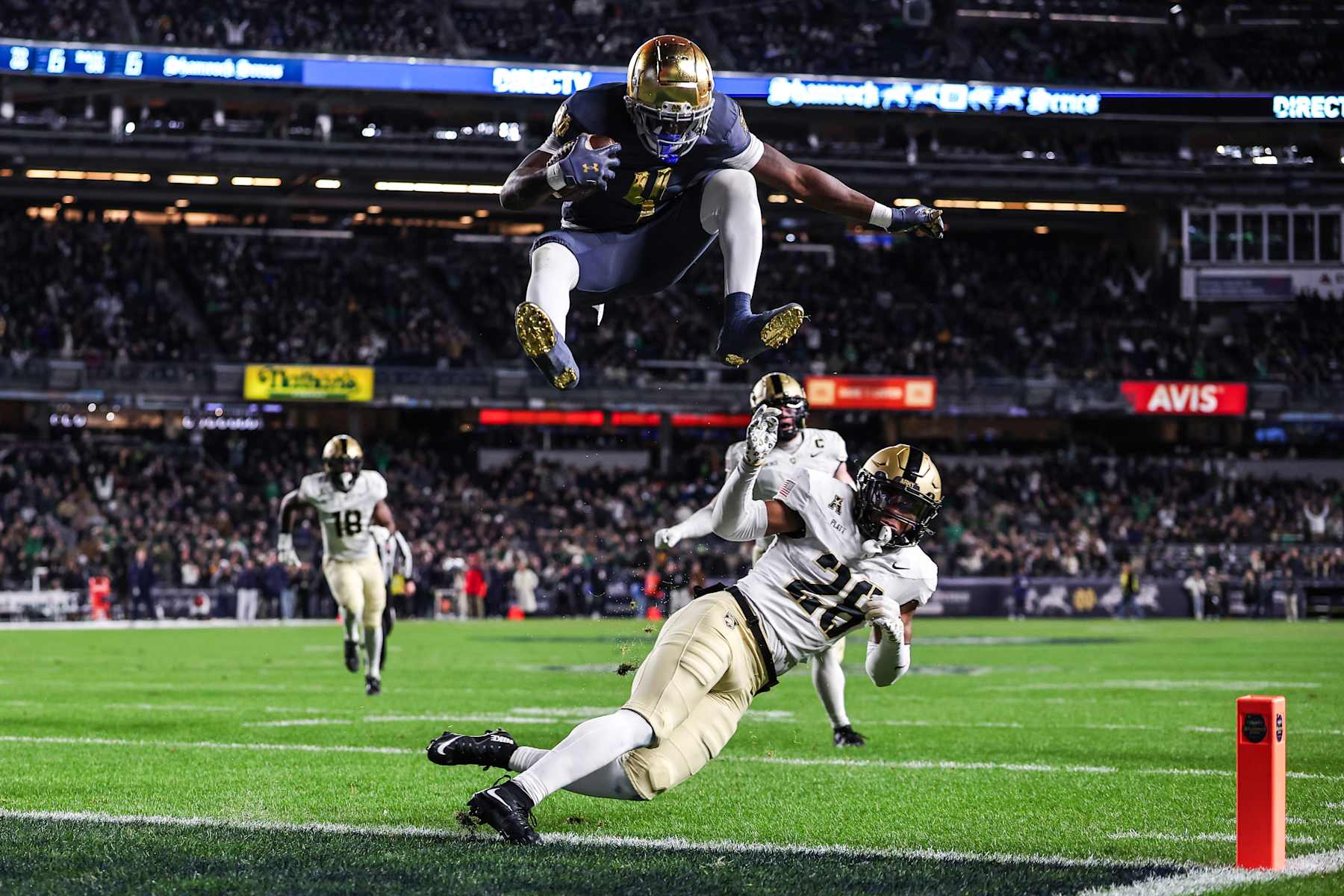 NEW YORK, NEW YORK - NOVEMBER 23: Jeremiyah Love #4 of the Notre Dame Fighting Irish hurdles over Donavon Platt #28 of the Army Black Knights to score a touchdown during the first quarter of the game at Yankee Stadium on November 23, 2024 in New York City. (Photo by Dustin Satloff/Getty Images)