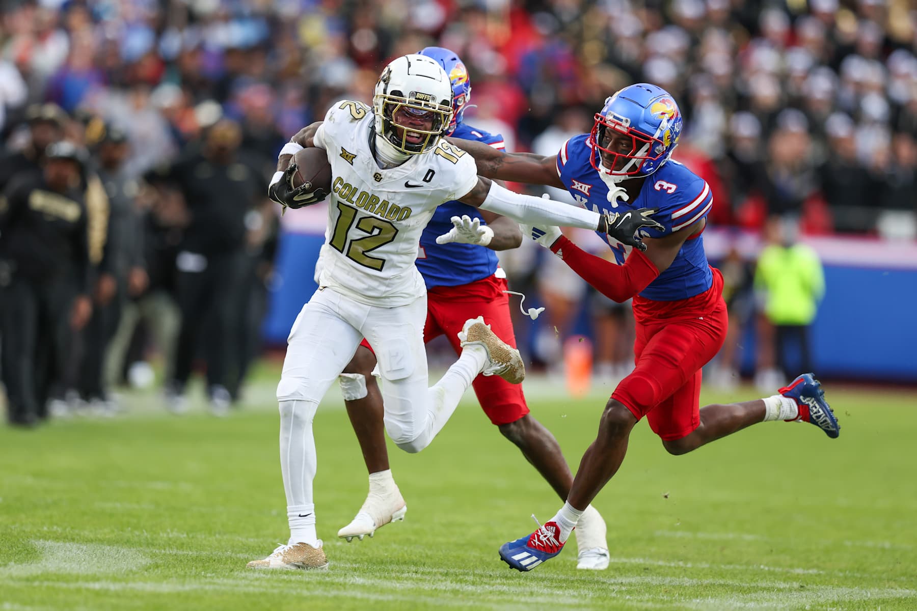KANSAS CITY, MO - NOVEMBER 23: Colorado Buffaloes wide receiver Travis Hunter (12) tries to run away from Kansas Jayhawks defenders in the second quarter of a Big 12 game between the Colorado Buffaloes and Kansas Jayhawks on November 23, 2024 at GEHA Field at Arrowhead Stadium in Kansas City, MO. (Photo by Scott Winters/Icon Sportswire via Getty Images)